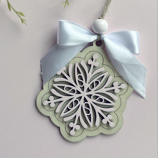 Decorative snowflake ornament with a white ribbon on a light background