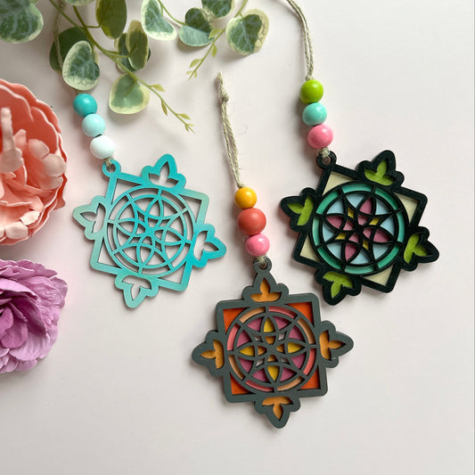 Decorative mandala-style ornaments with beads on a white surface with flowers and greenery.