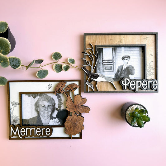 Two framed photographs of an elderly couple on a pink wall with decorative elements.