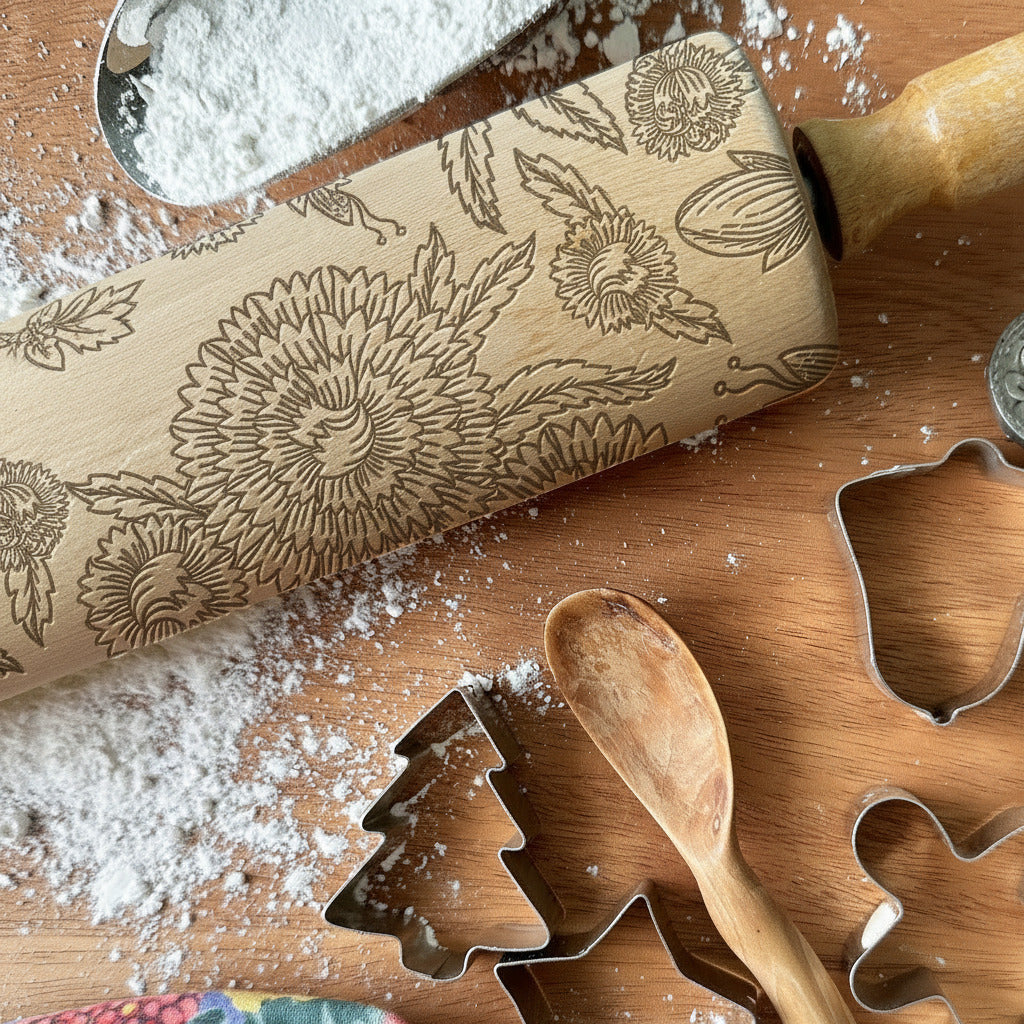 Wooden rolling pin with embossed designs and cookie cutters on a wooden surface with flour.