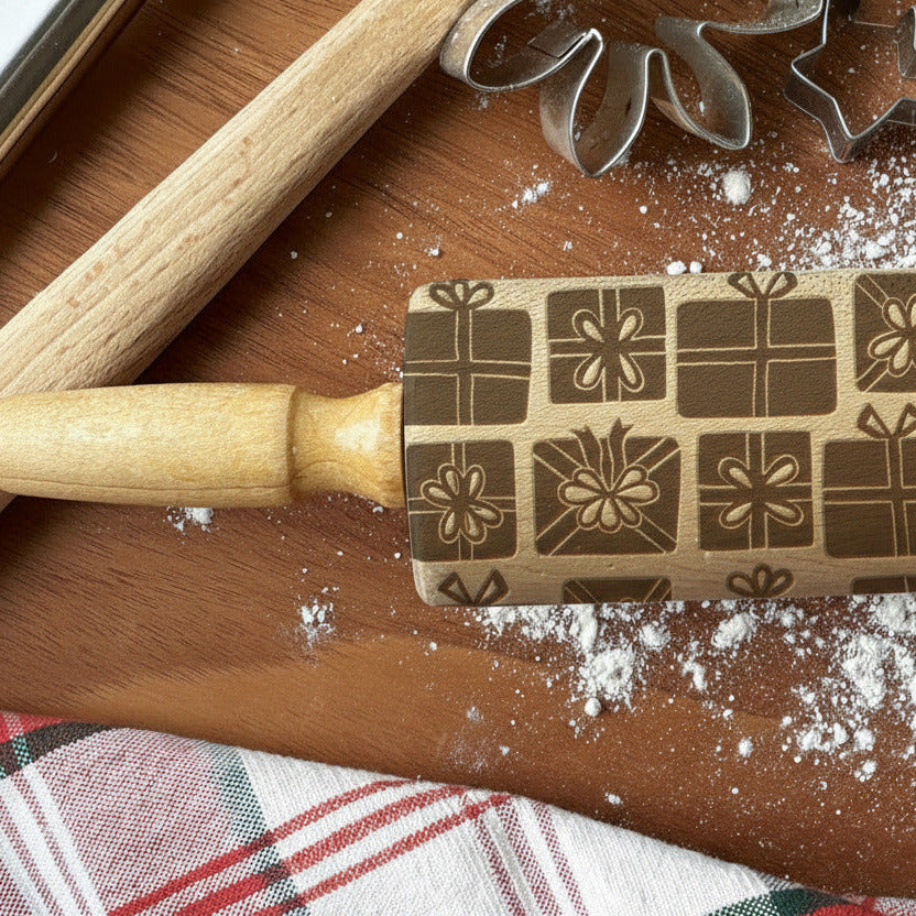 Wooden rolling pin with decorative patterns on a wooden surface with flour and plaid fabric.