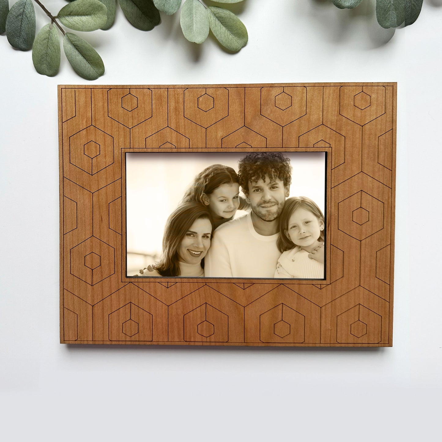 Wooden picture frame with geometric patterns holding a family photo on a white background.