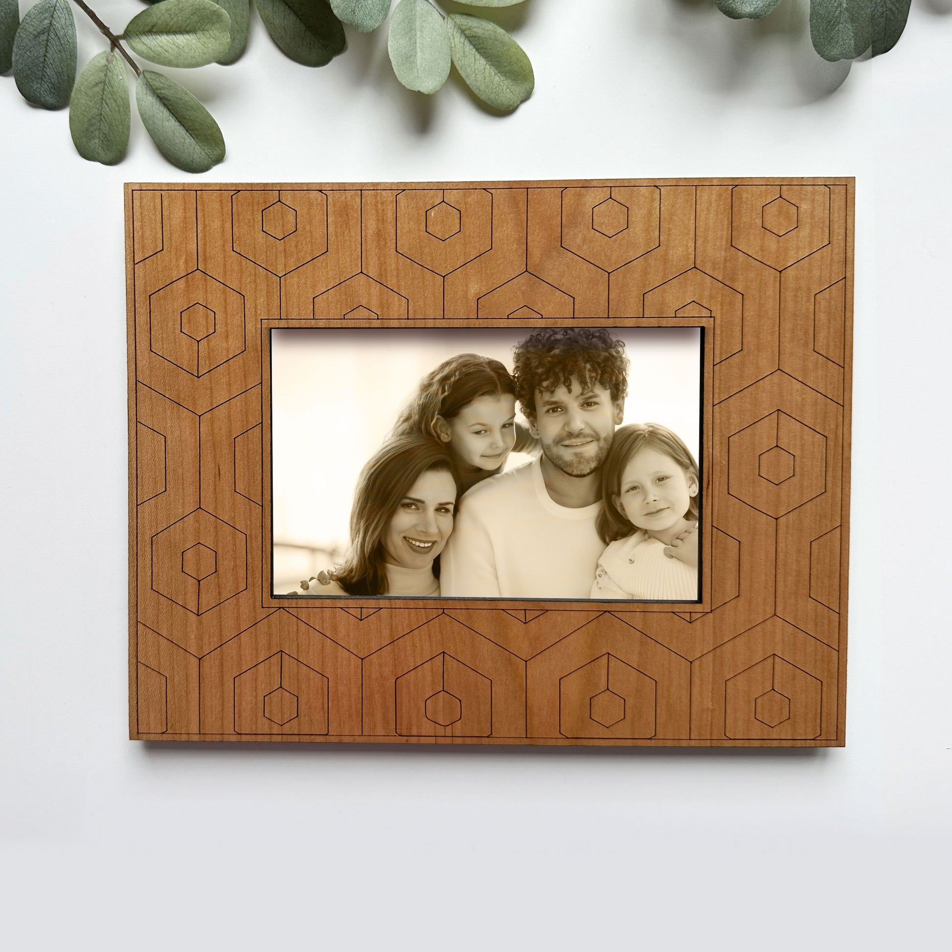 Wooden picture frame with geometric patterns holding a family photo on a white background.