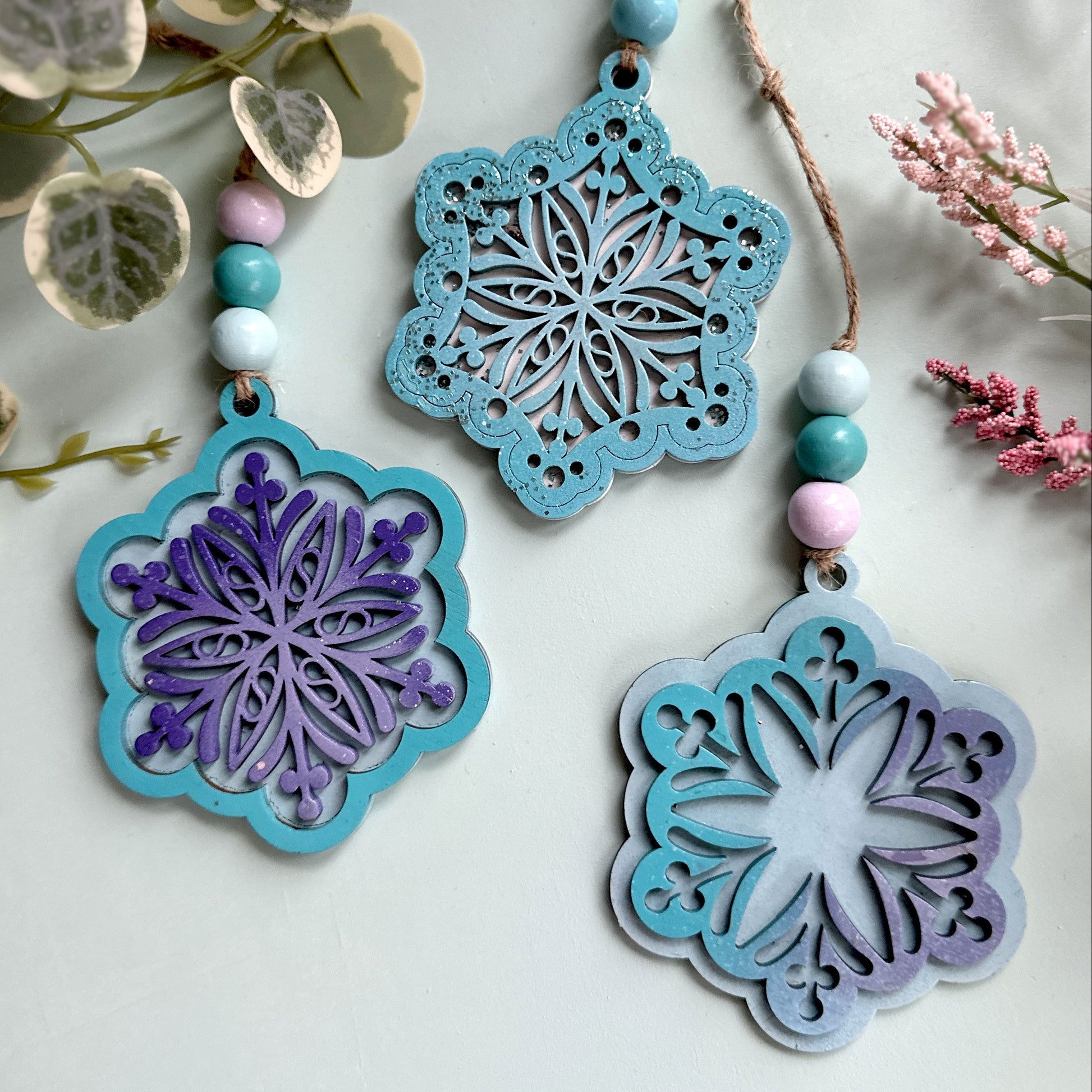 Decorative snowflake ornaments with beads on a light background, featuring the brand 'DDWORKS'.