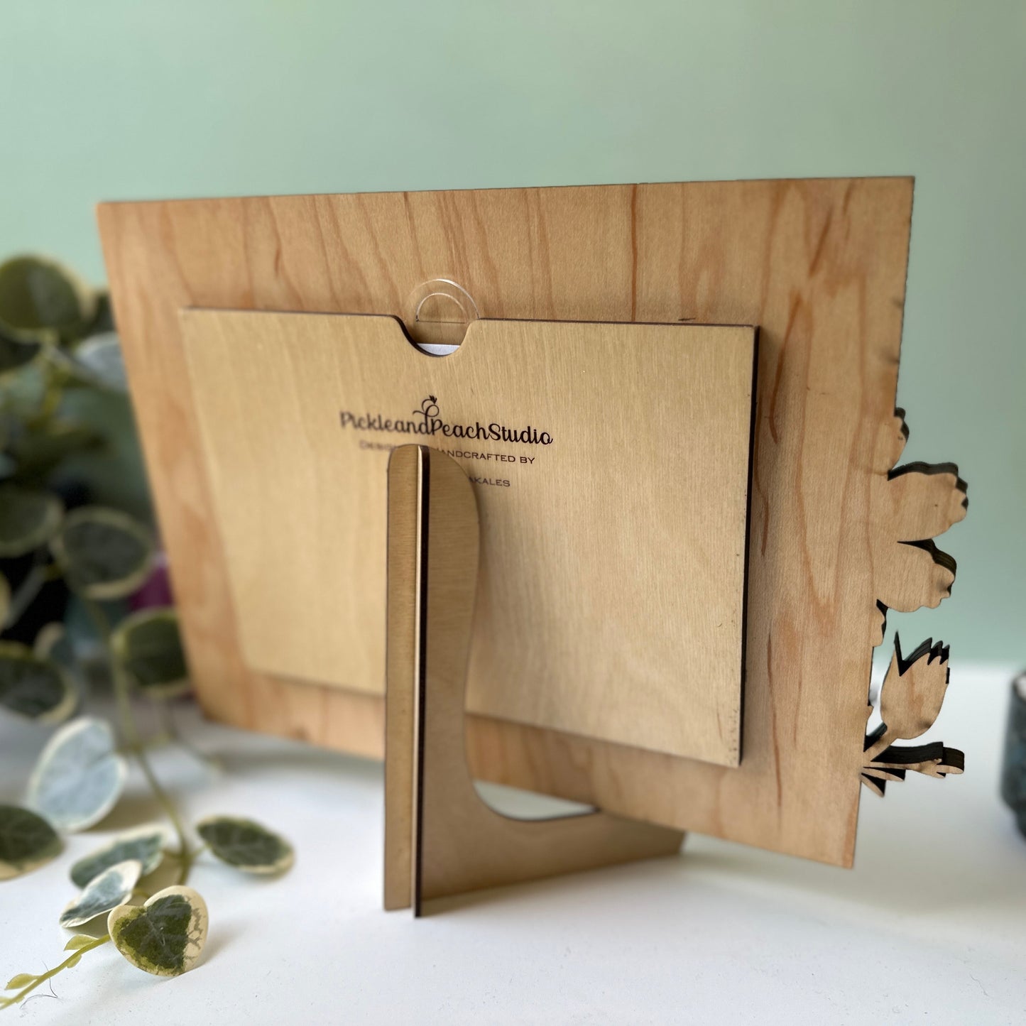 Wooden photo frame with a plant and decorative items in the background