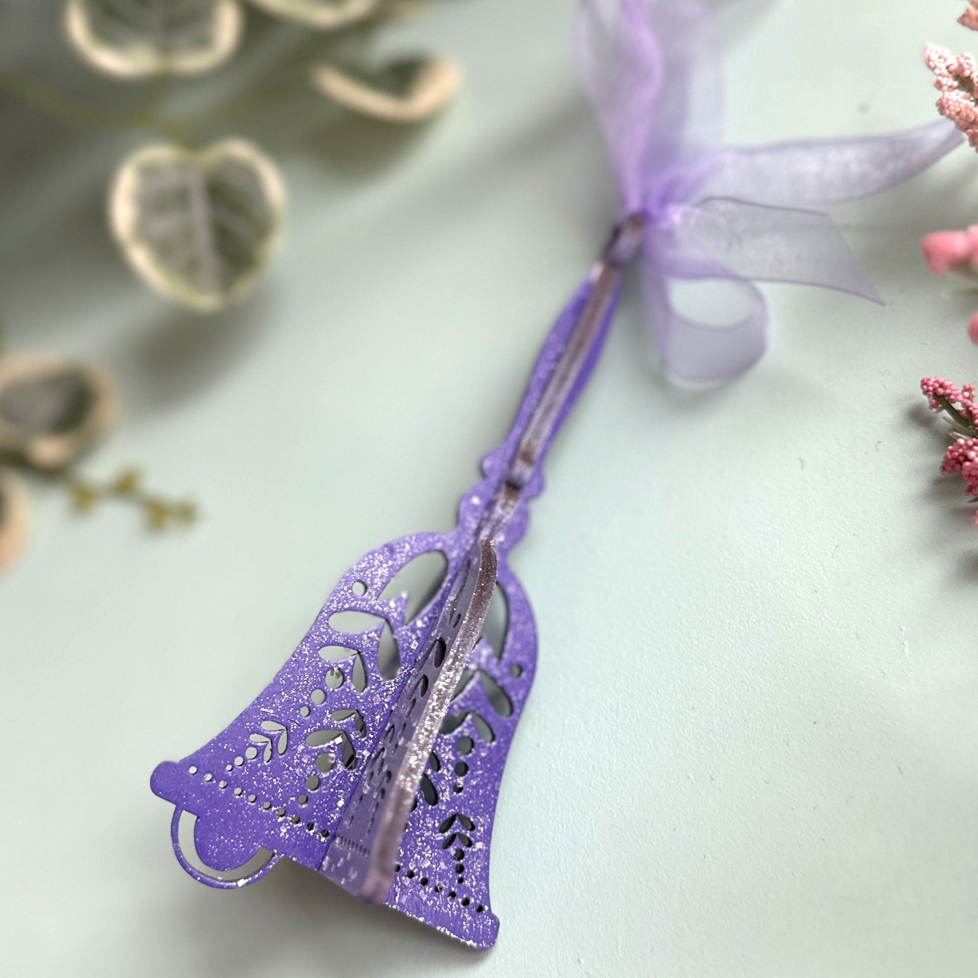 Purple decorative bell with a ribbon on a light background