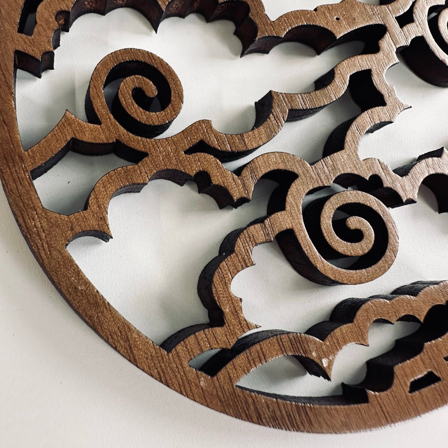 Wooden decorative coaster with intricate patterns on a light background