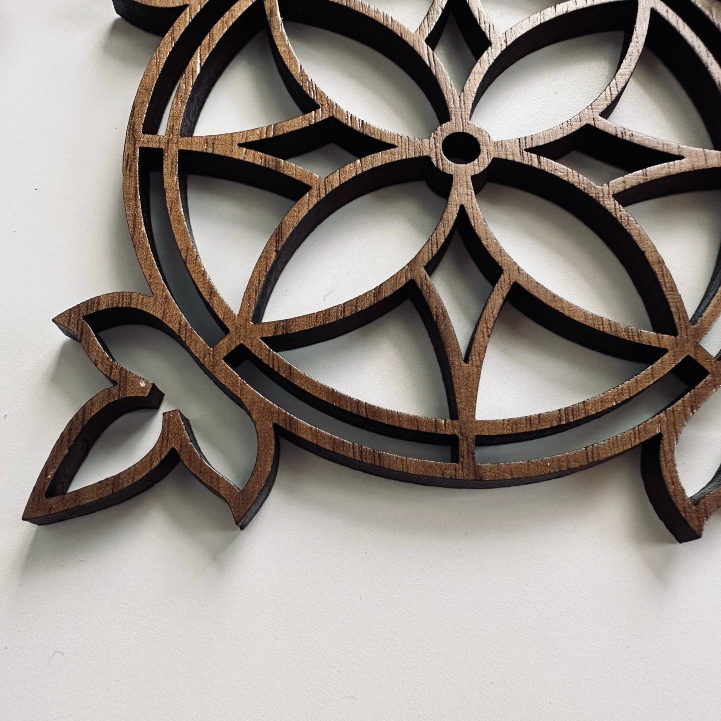 Decorative wooden coaster with intricate cut-out patterns on a white background