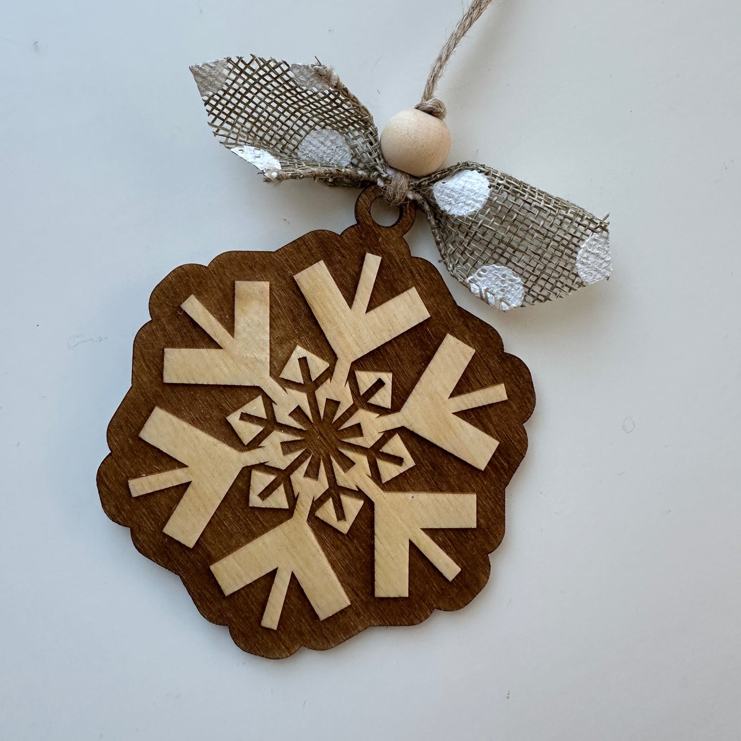 Decorative snowflake ornament with brown border and beige center on a white background