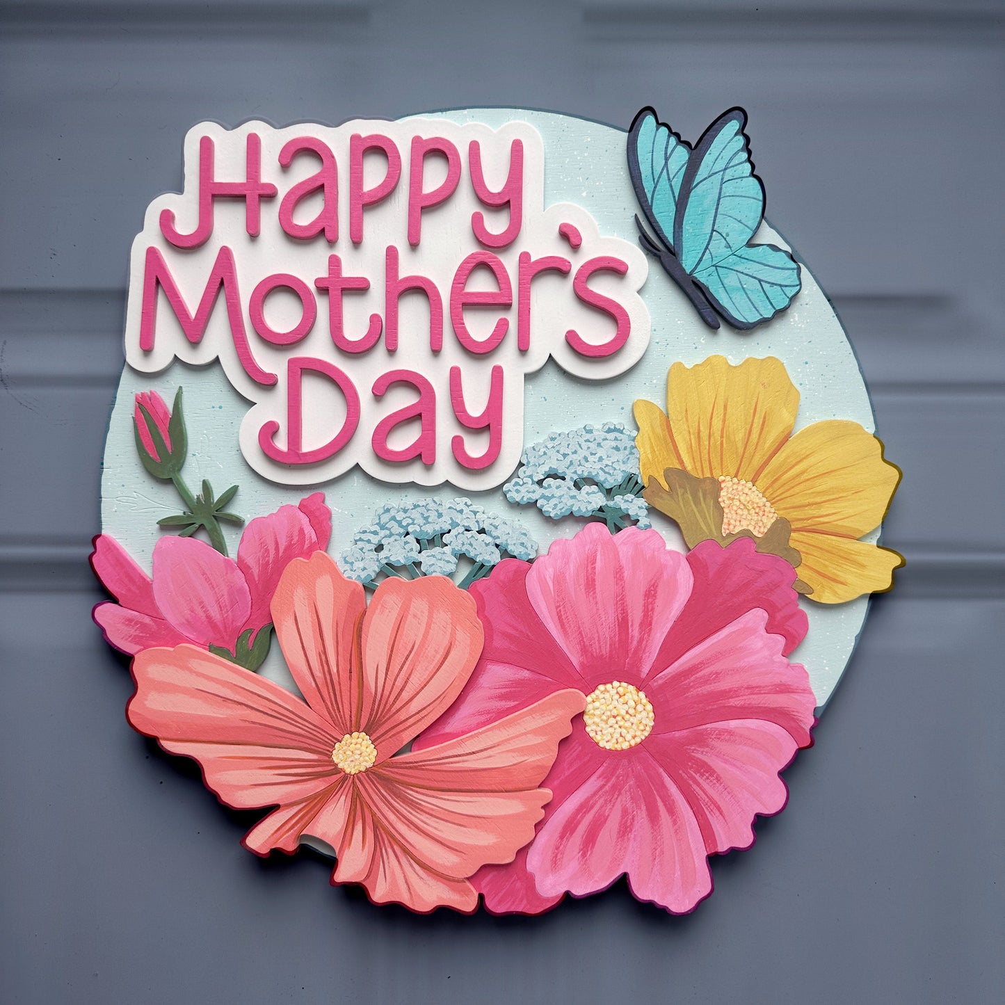 Decorative sign with 'Happy Mother's Day' text and flowers on a gray background