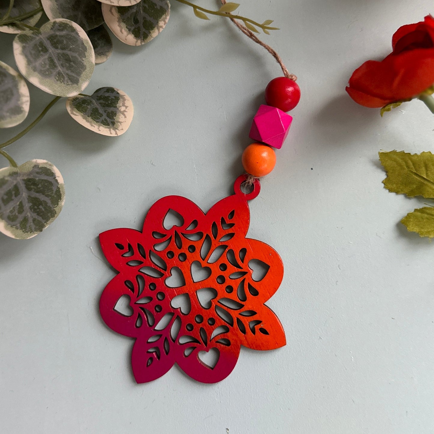 Decorative red and pink ornament with floral elements on a light background