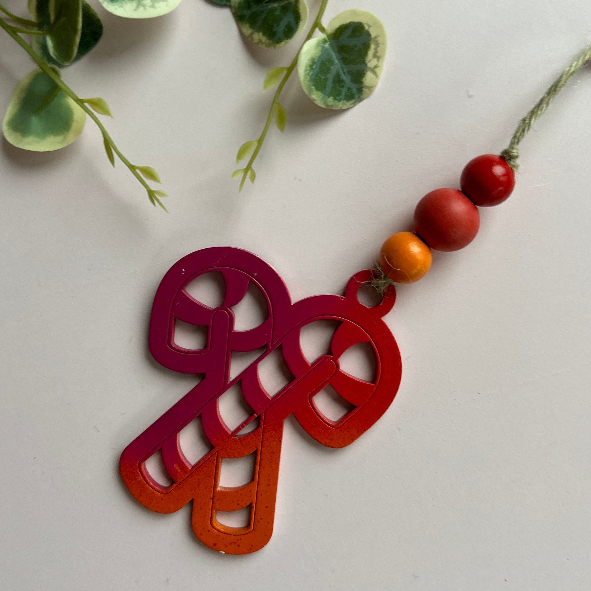 Decorative candy cane ornament with beads on a white background.
