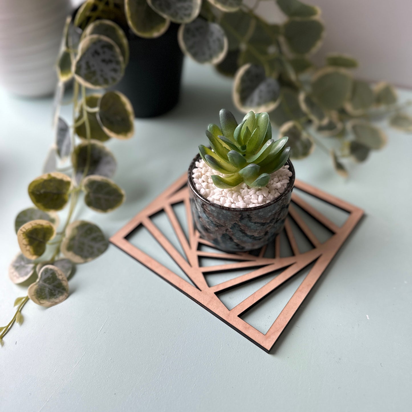 A potted plane on a laser-cut trivet with a decorative design