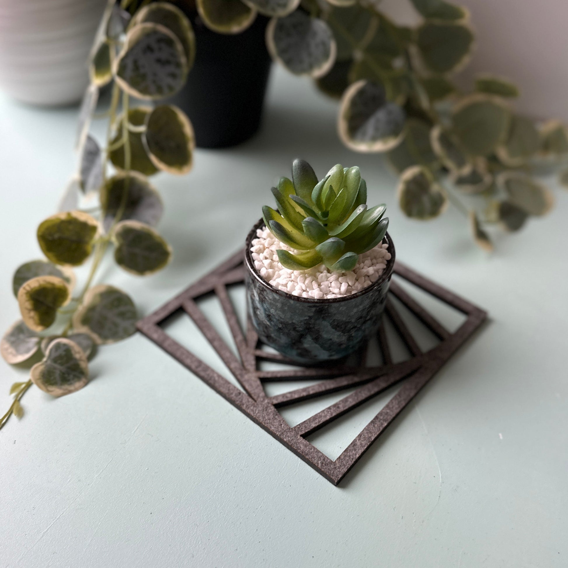 A potted plant  on a laser-cut trivet with a decorative design