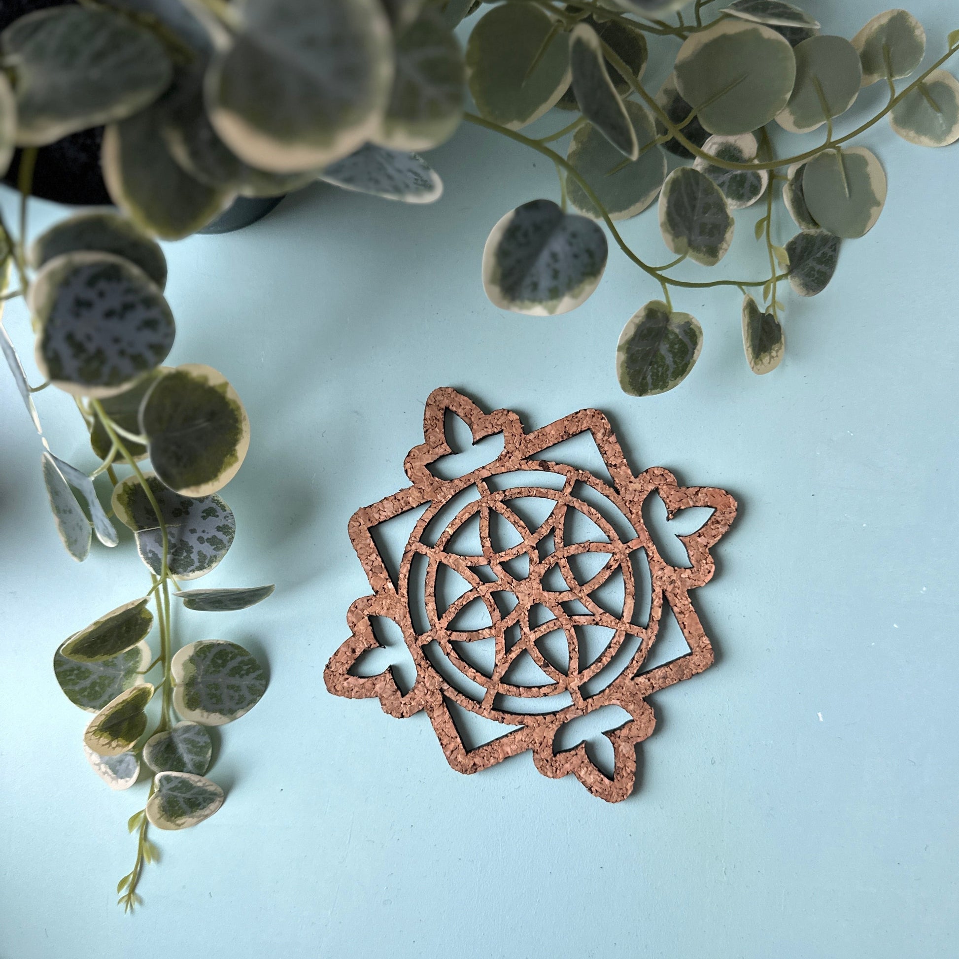 A cork trivet in a stained glass design on a blue background