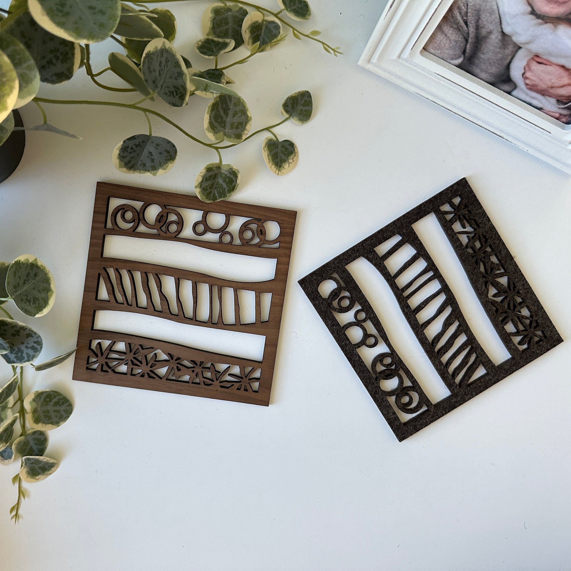 Decorative trivets with intricate designs on a white surface with greenery.