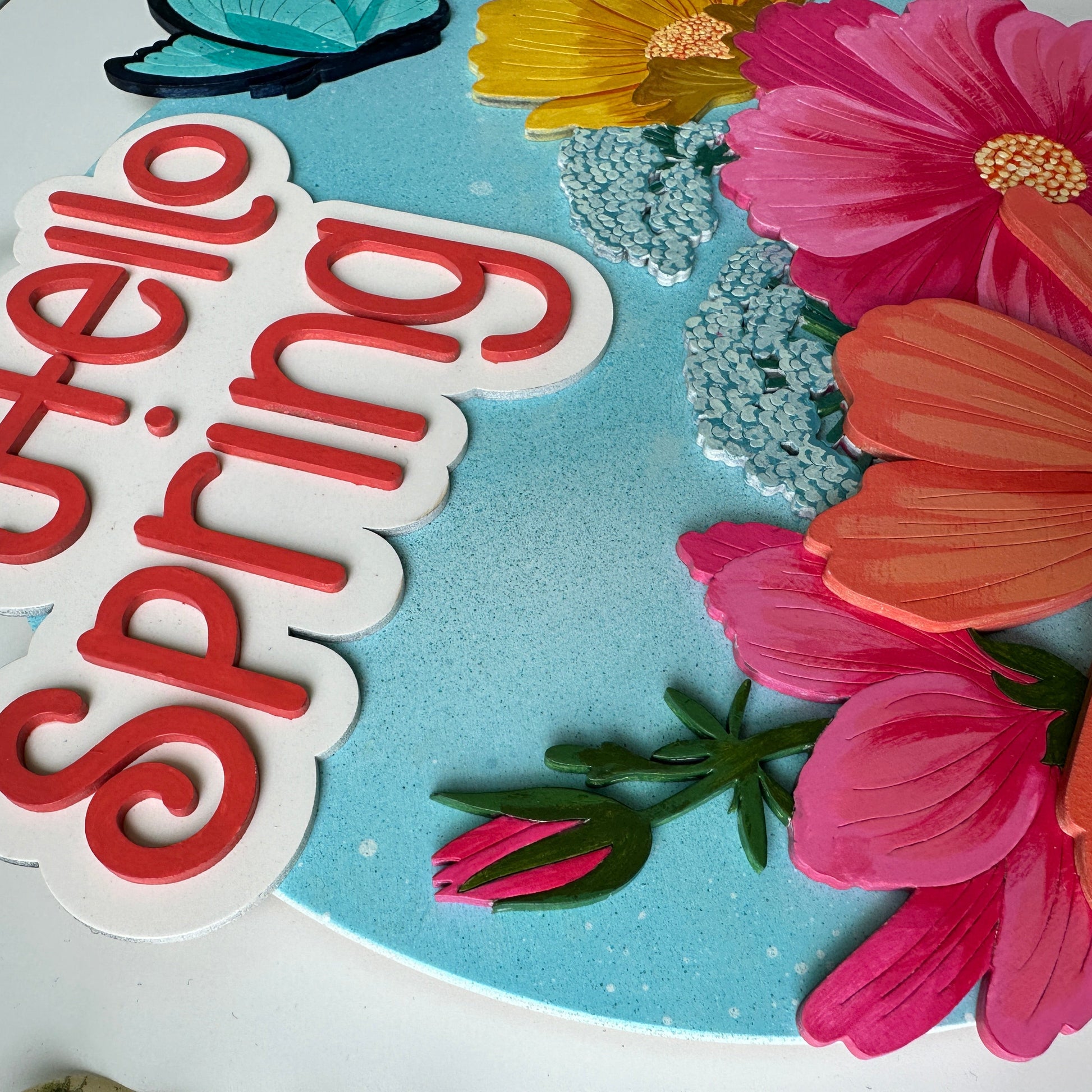 Decorative paper with 'Hello Spring' text and colorful flowers on a blue background