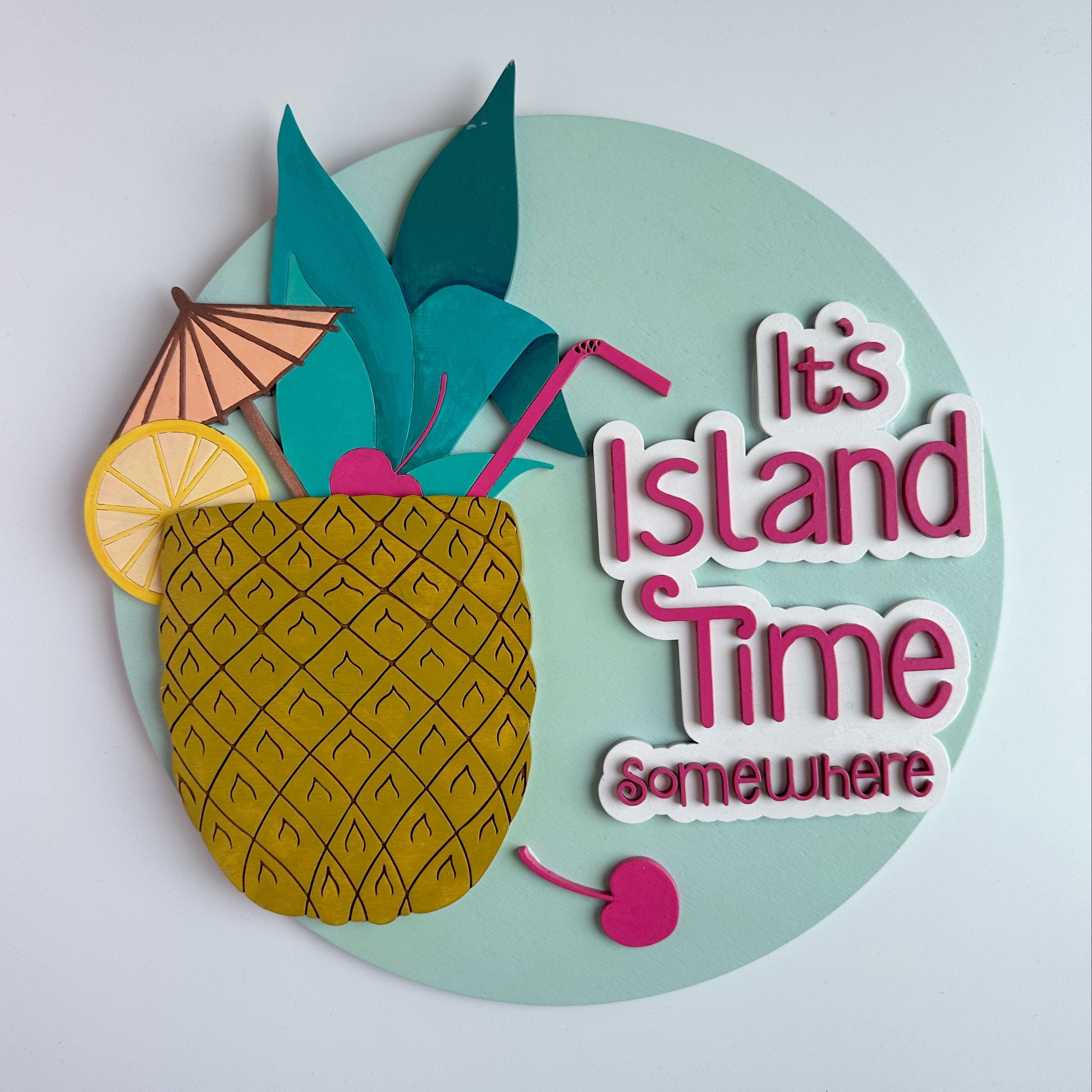 Decorative sign with pineapple, umbrella, and text 'It's Island Time Somewhere' on a light blue background