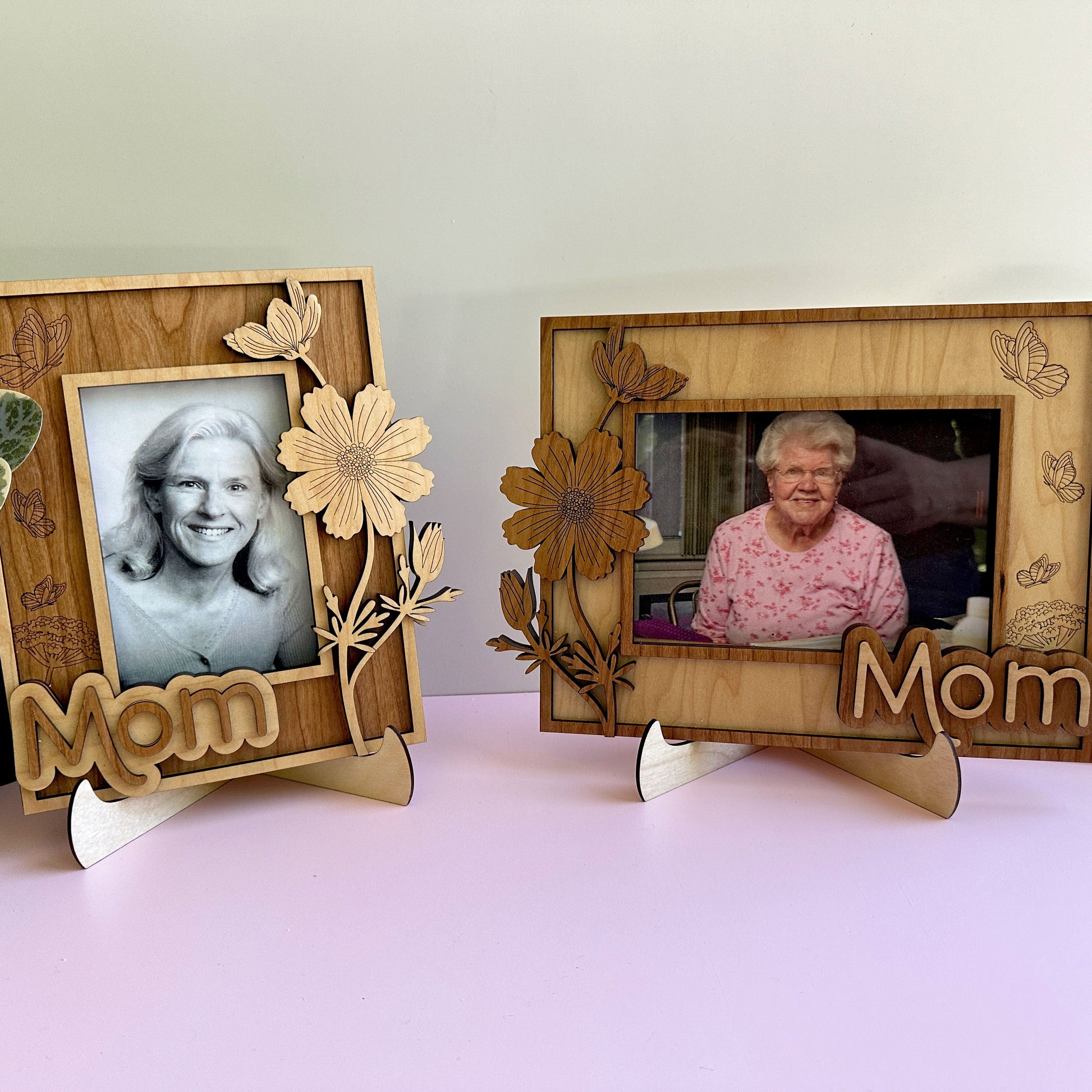 Two wooden photo frames with floral designs and 'Mom' text on a light pink surface.