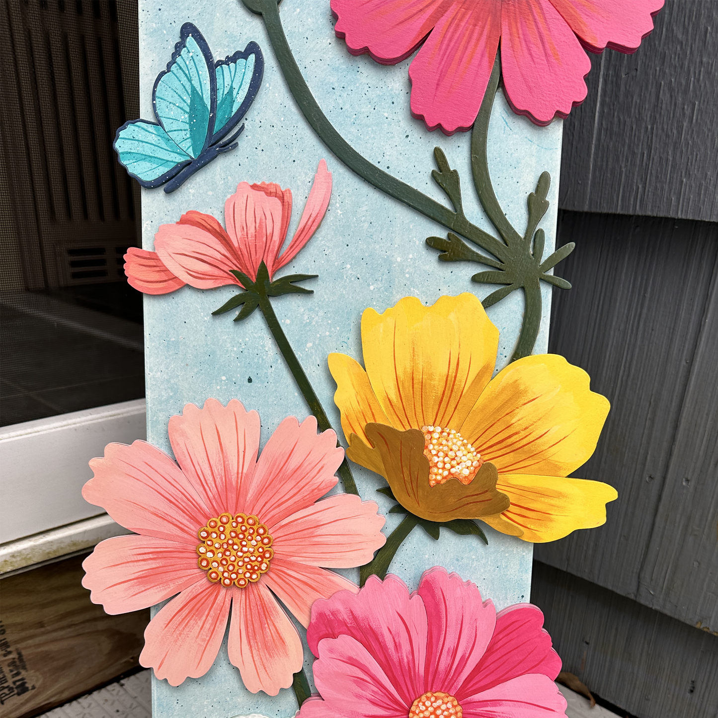 Decorative sign with colorful flowers and butterflies on a wooden surface