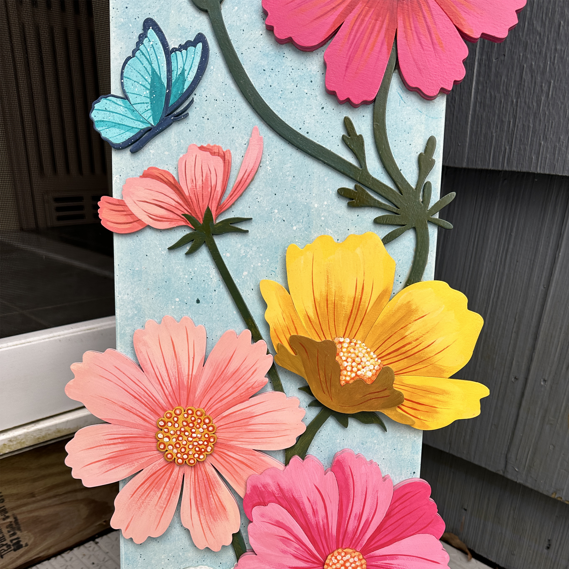 Decorative sign with colorful flowers and butterflies on a wooden surface