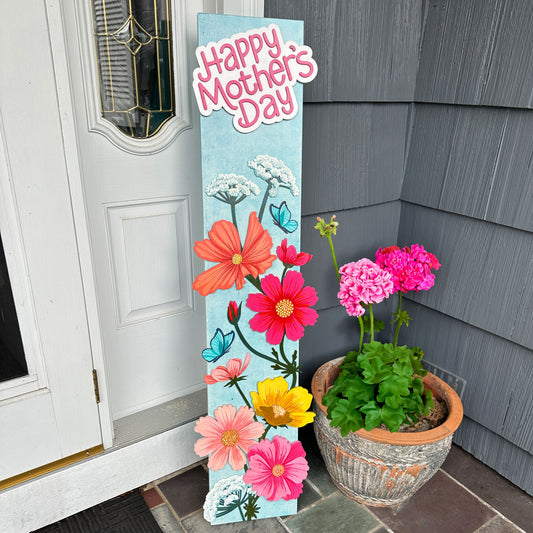 Decorative sign with flowers and 'Happy Mother's Day' text next to a potted plant on a porch.