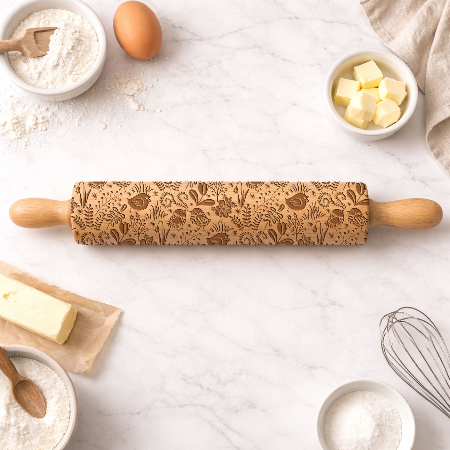 Decorative rolling pin with embossed patterns on a kitchen counter with baking ingredients.