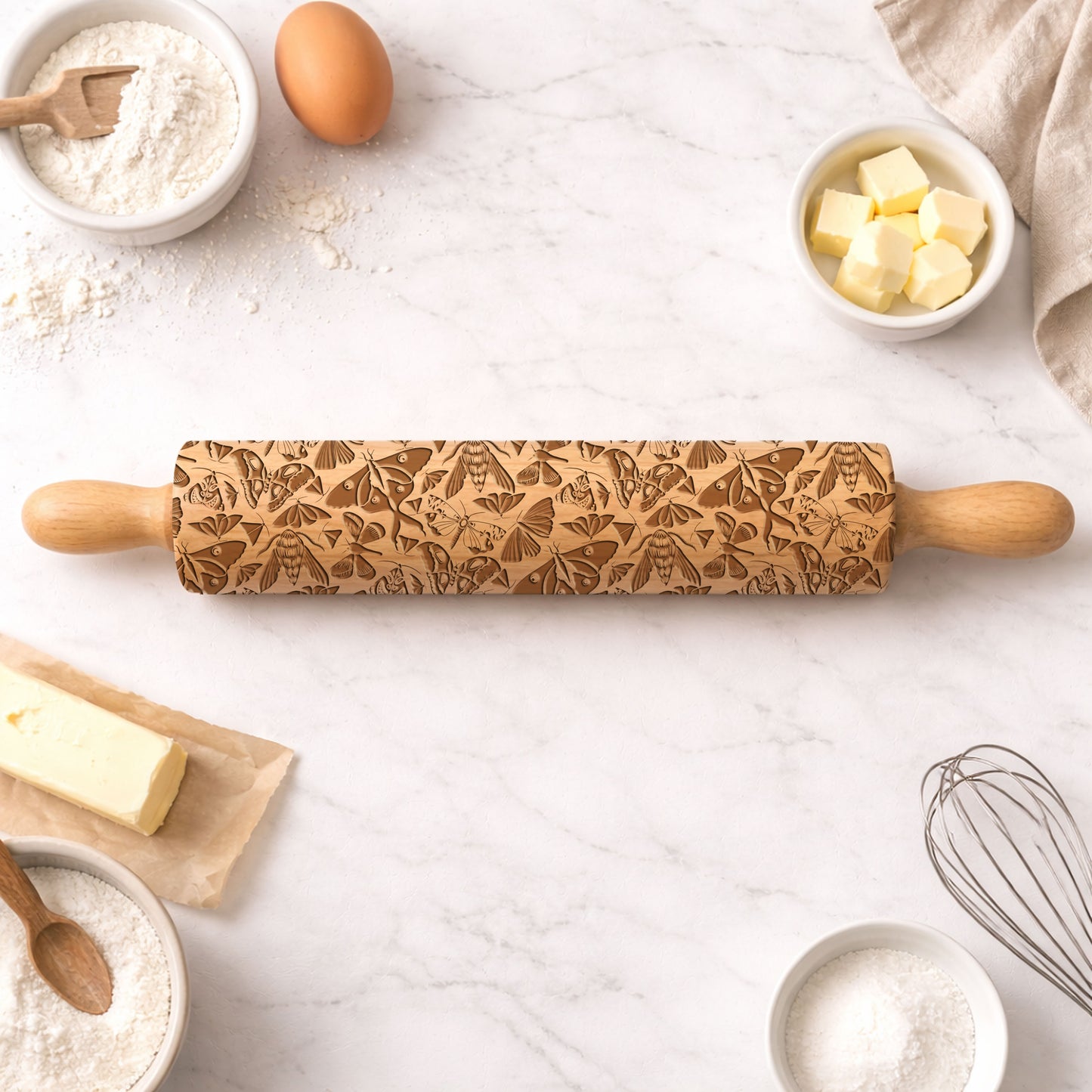 Wooden rolling pin with embossed designs on a kitchen counter with baking ingredients.