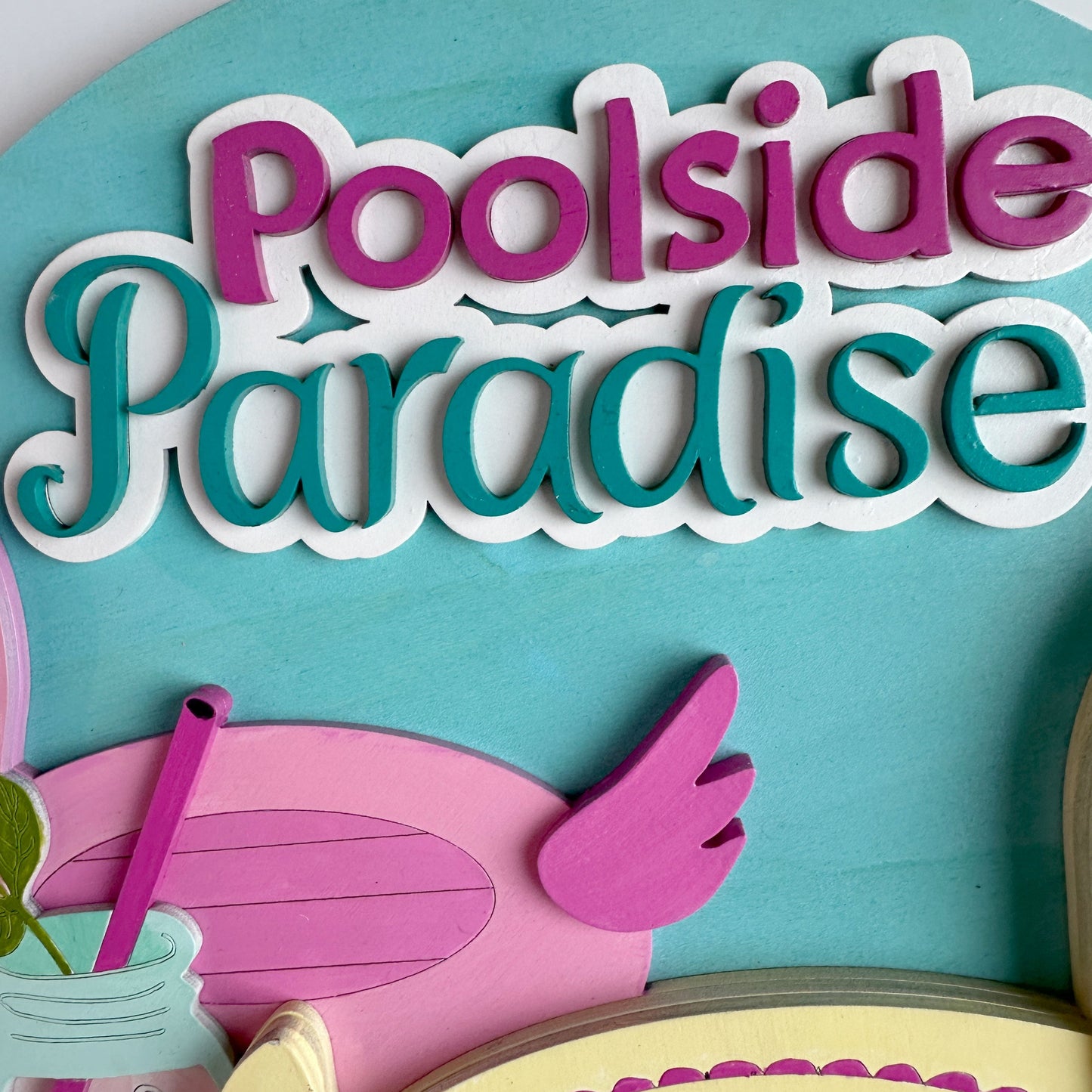 Decorative sign with 'Poolside Paradise' text and pool-themed graphics on a blue background