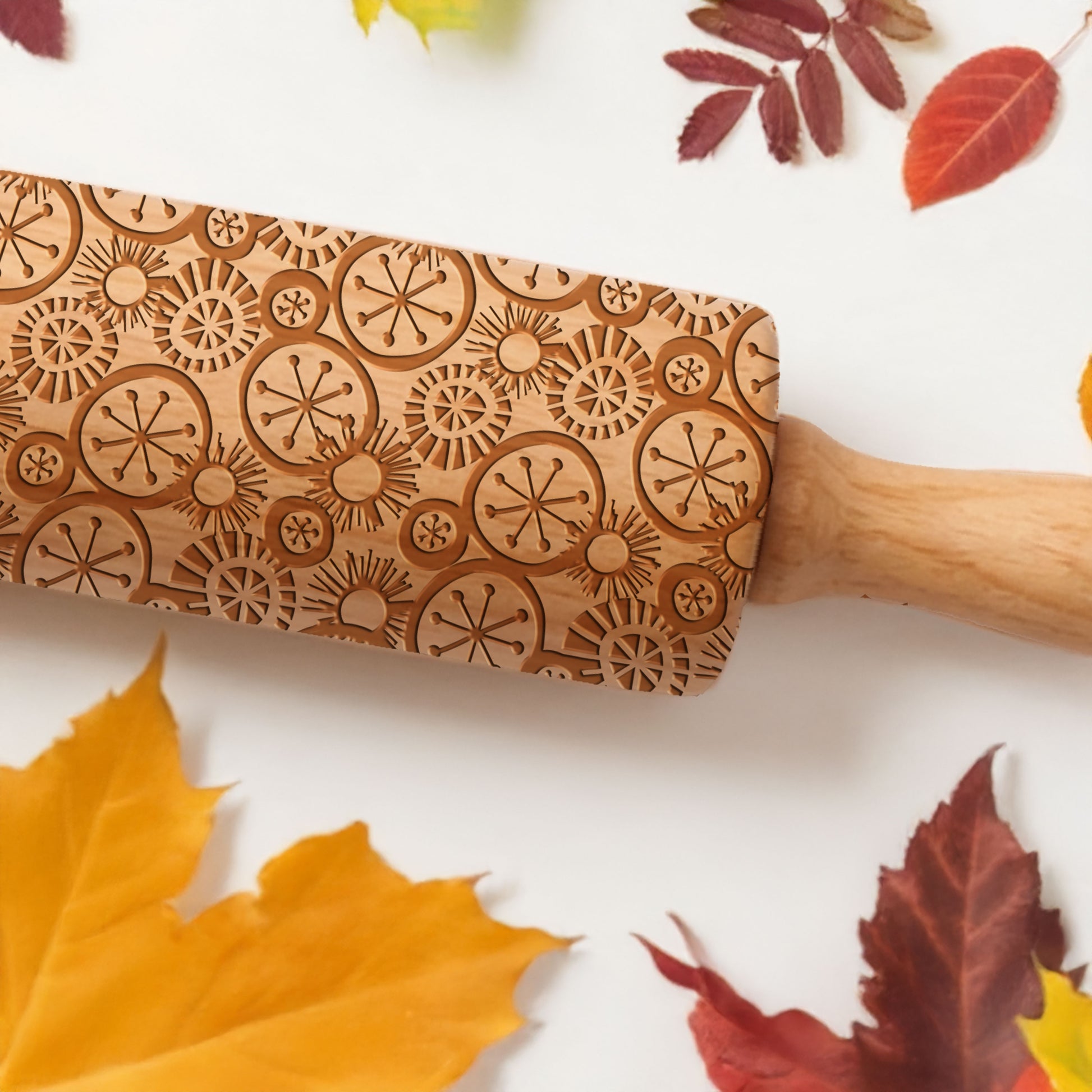 Wooden rolling pin with autumn leaf decorations on a white background