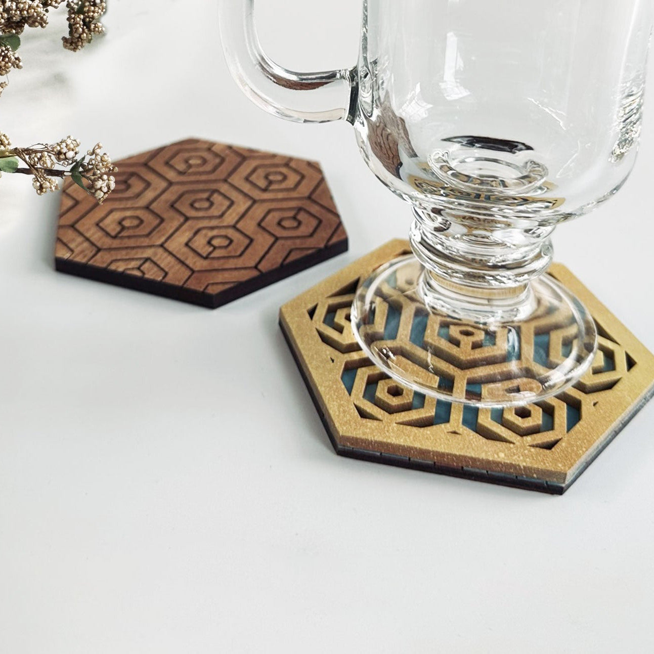 Hexagonal coasters with geometric pattern on a white surface with a glass of beer.