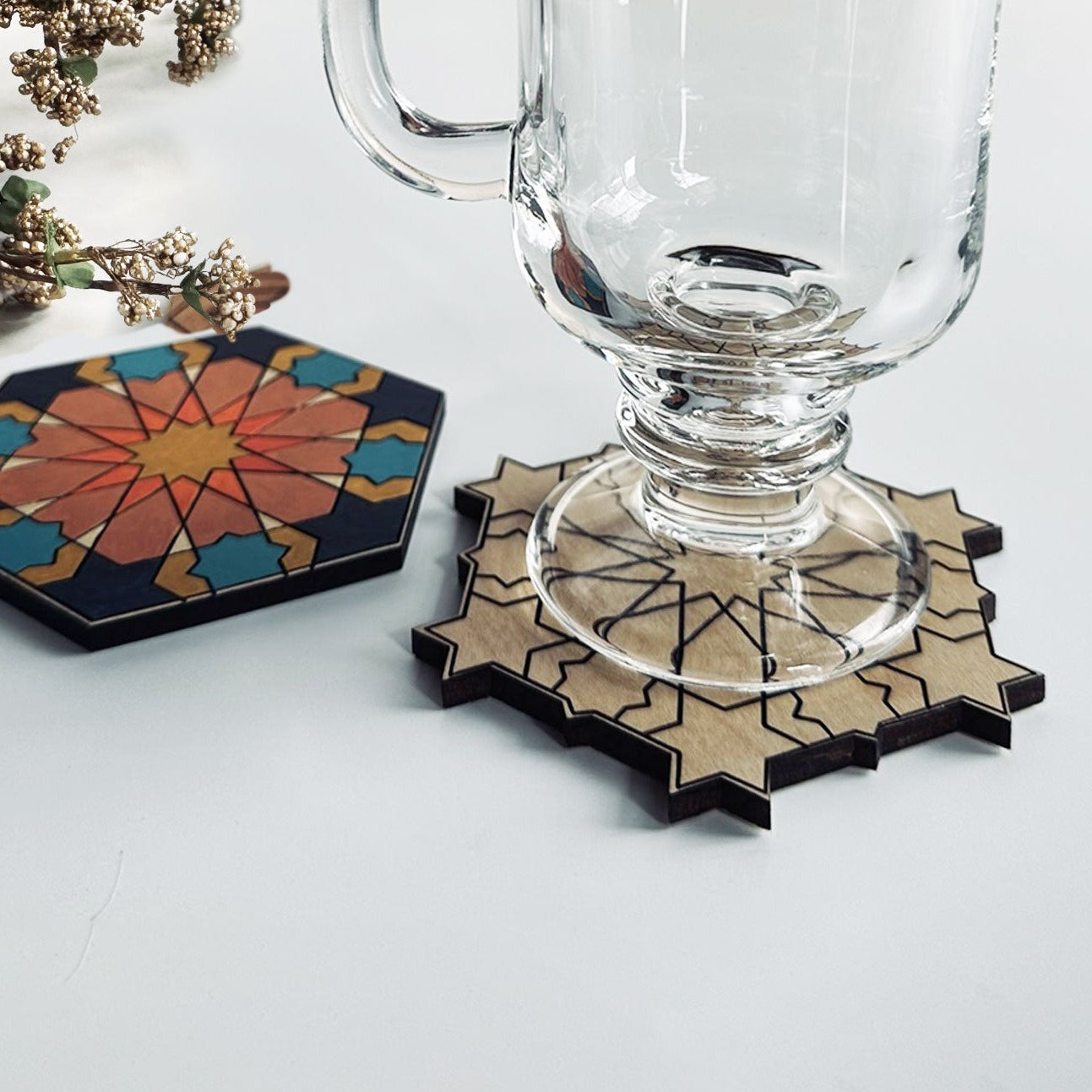 Two geometric coasters with floral and abstract designs on a white surface.