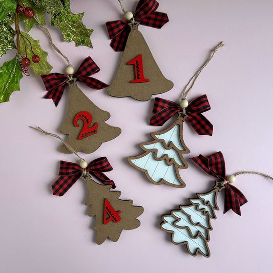 Laser-cut layered Christmas tree ornaments with buffalo plaid ribbon bows, hanging against a holiday backdrop