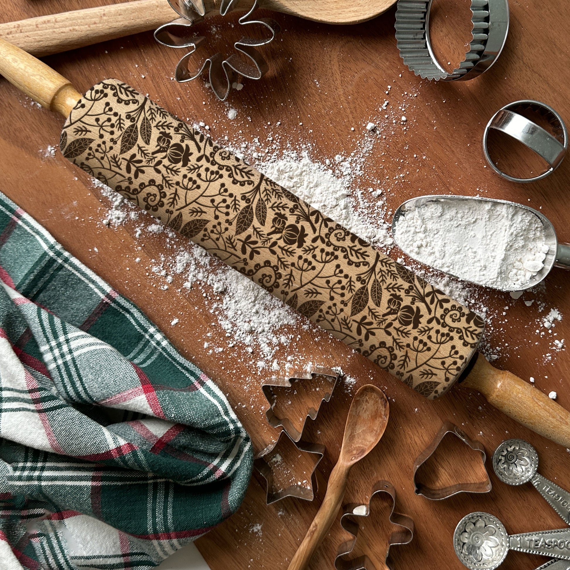 Decorative rolling pin with embossed pattern on a wooden surface with baking tools.