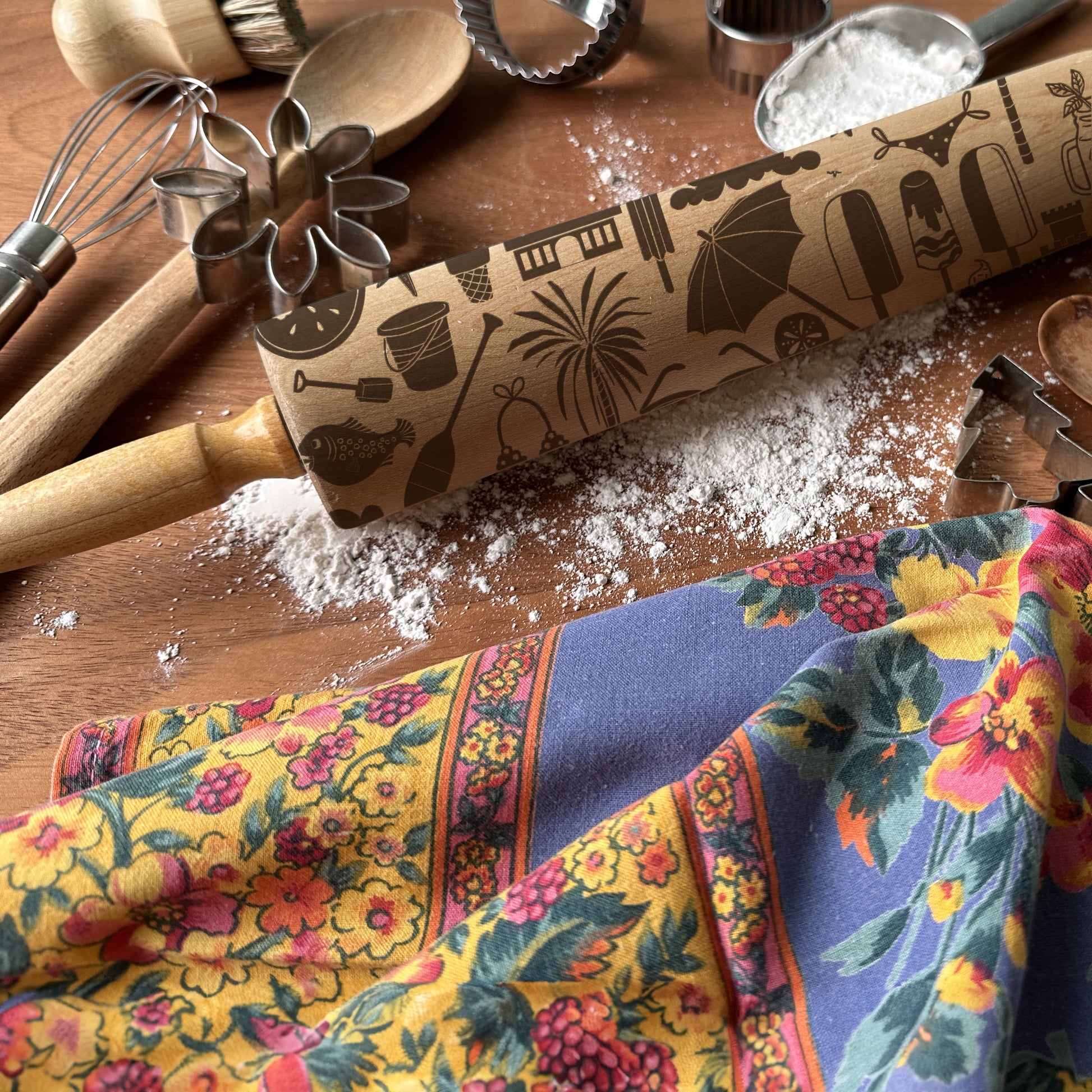 Rolling pin with decorative patterns on a wooden surface with kitchen utensils and a colorful towel.