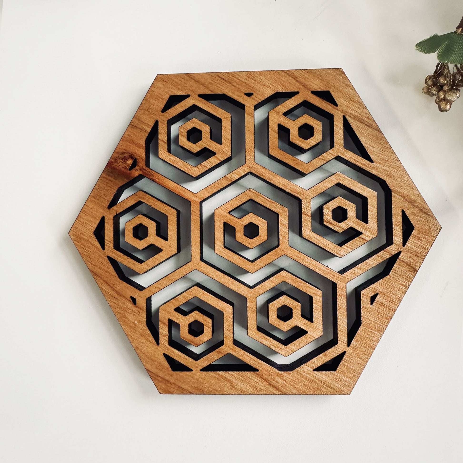 A wooden laser-cut hexagonal coaster with a honeycomb design on on a white background.
