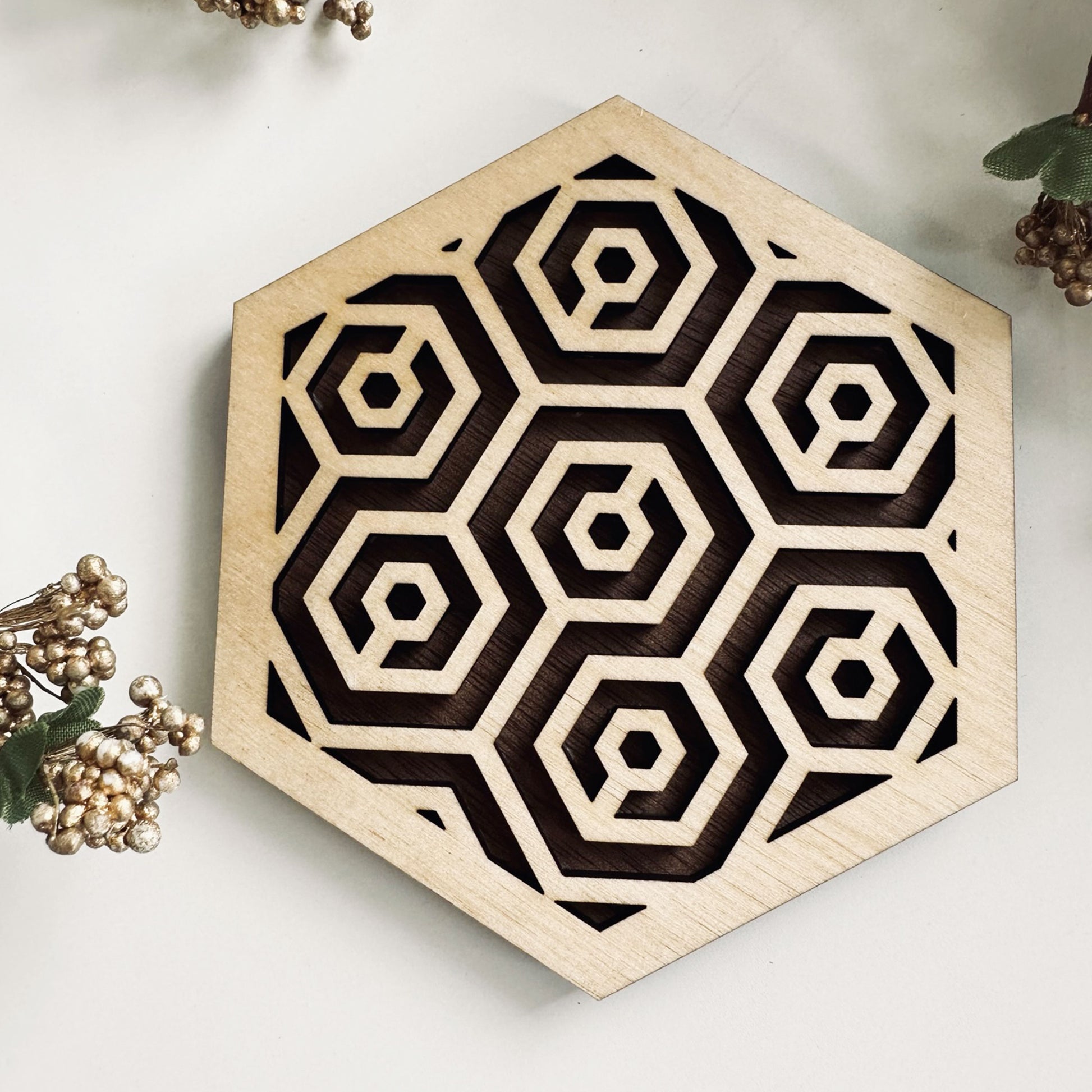 A wooden laser-cut hexagonal coaster with a honeycomb design on on a white background.