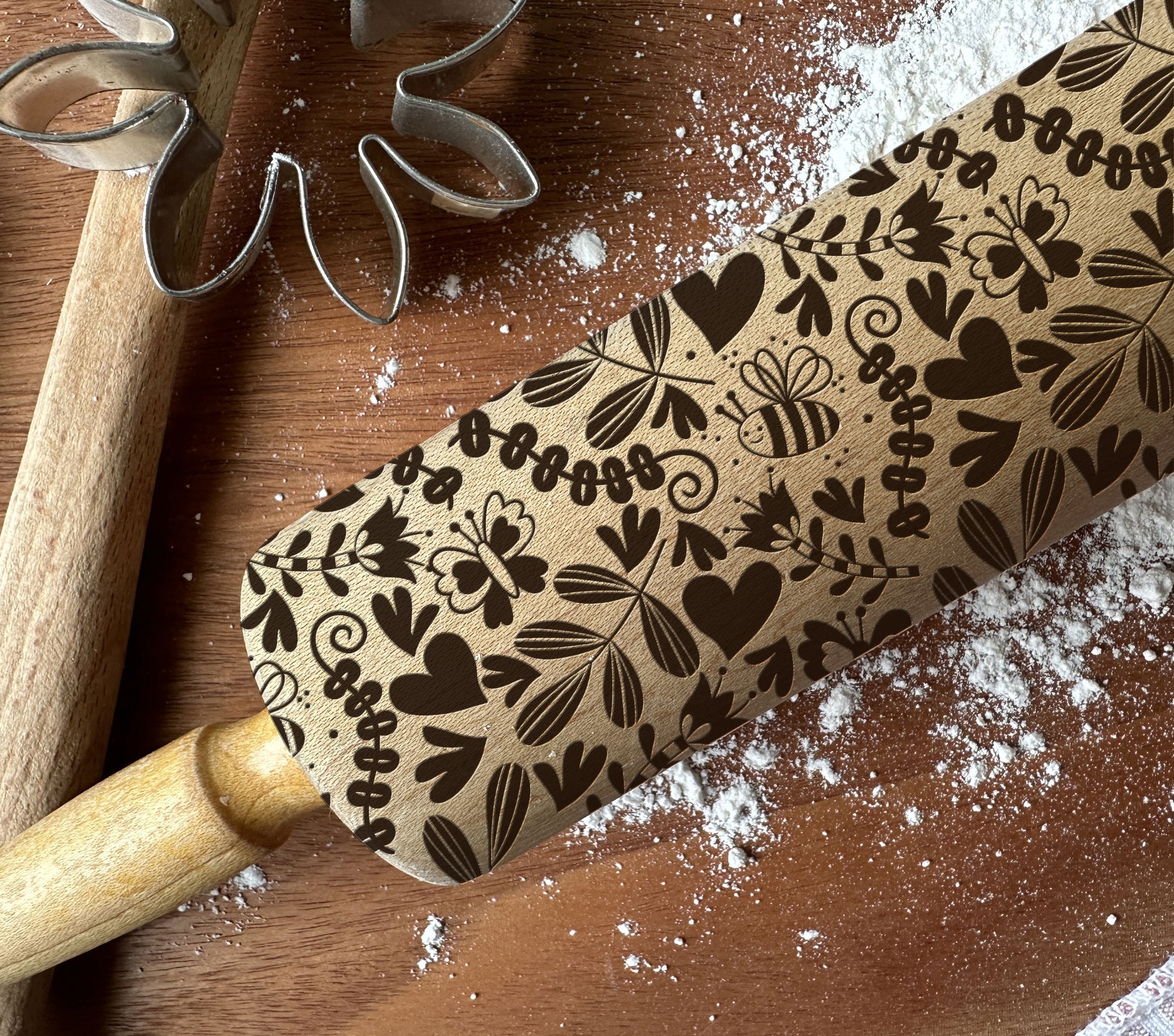 Wooden rolling pin with floral pattern on a wooden surface with flour.