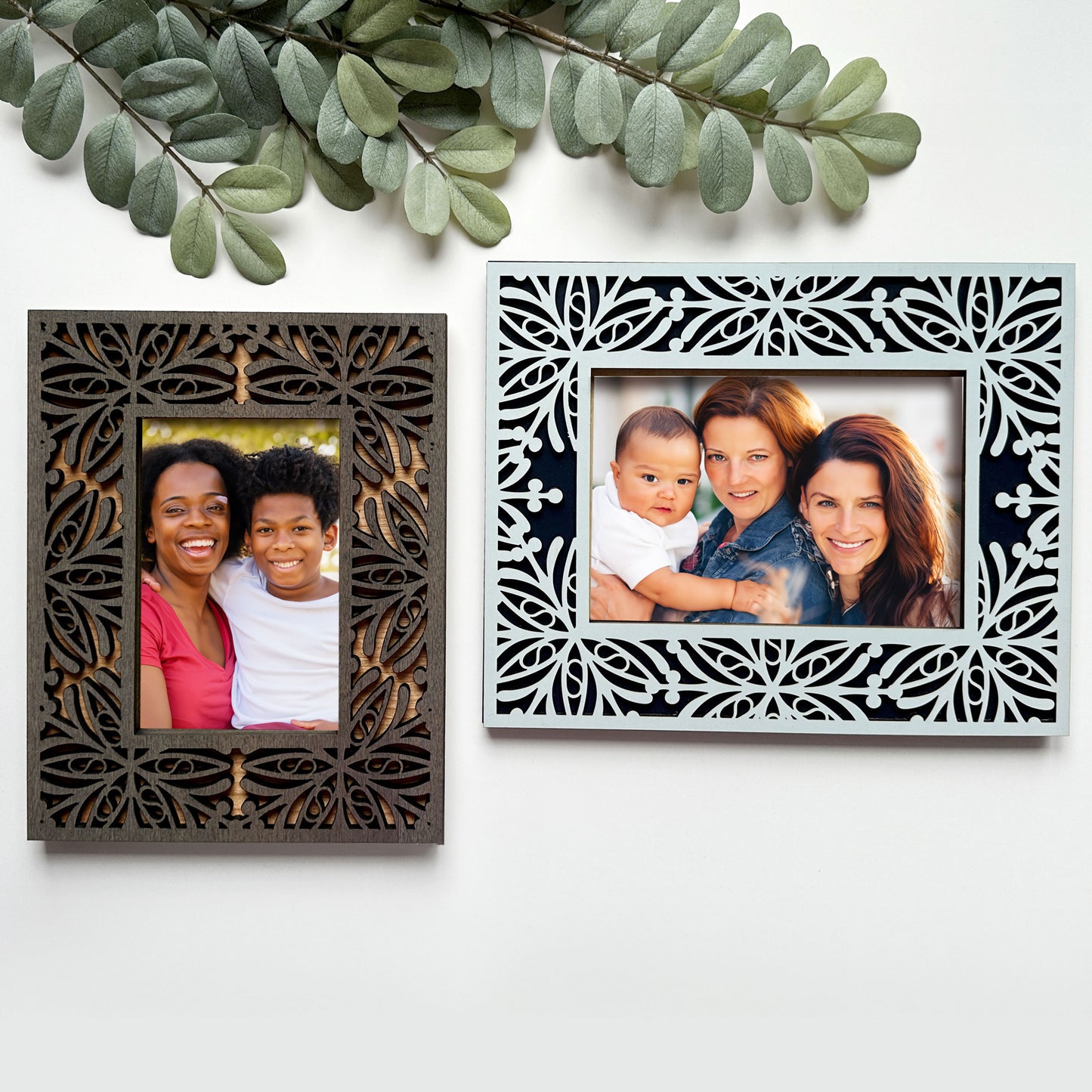 Two decorative picture frames with family photos on a white background with green leaves.