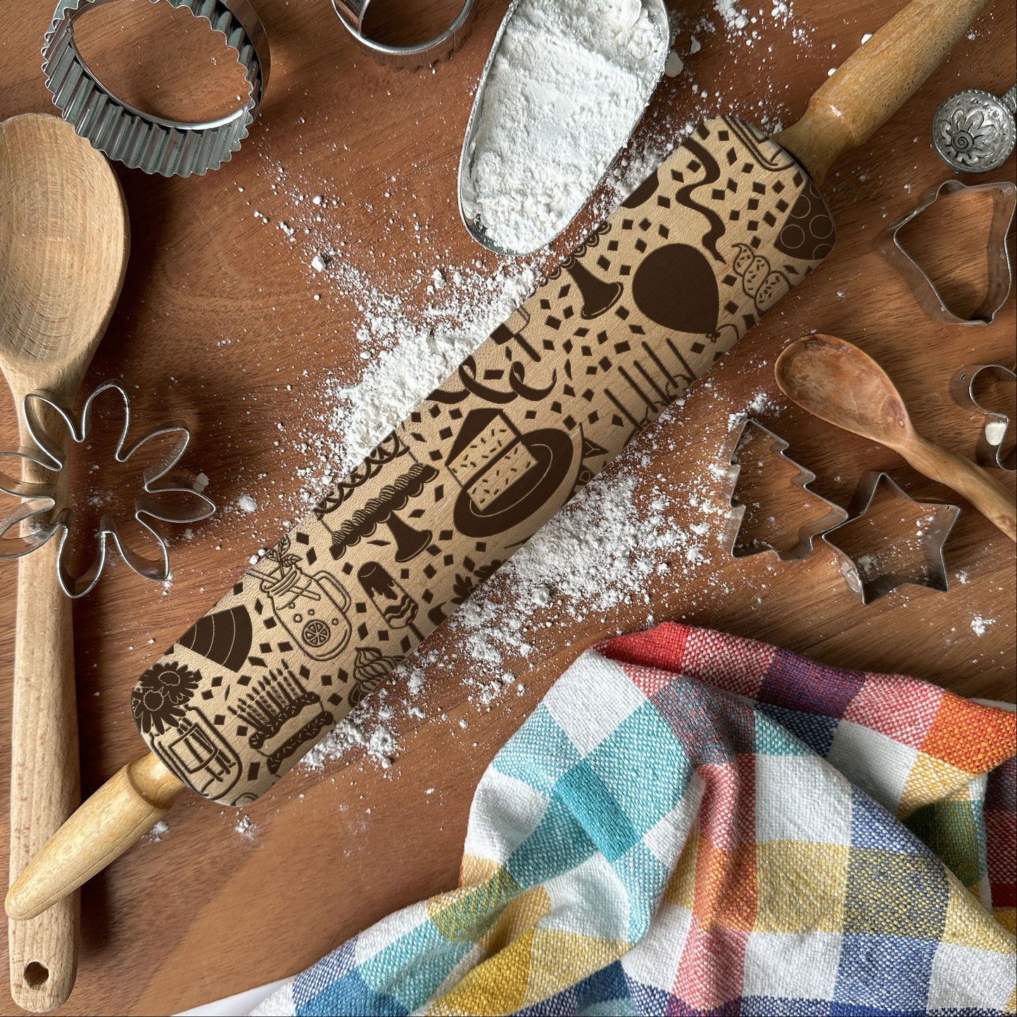 Wooden rolling pin with embossed designs on a wooden surface with baking tools and flour.
