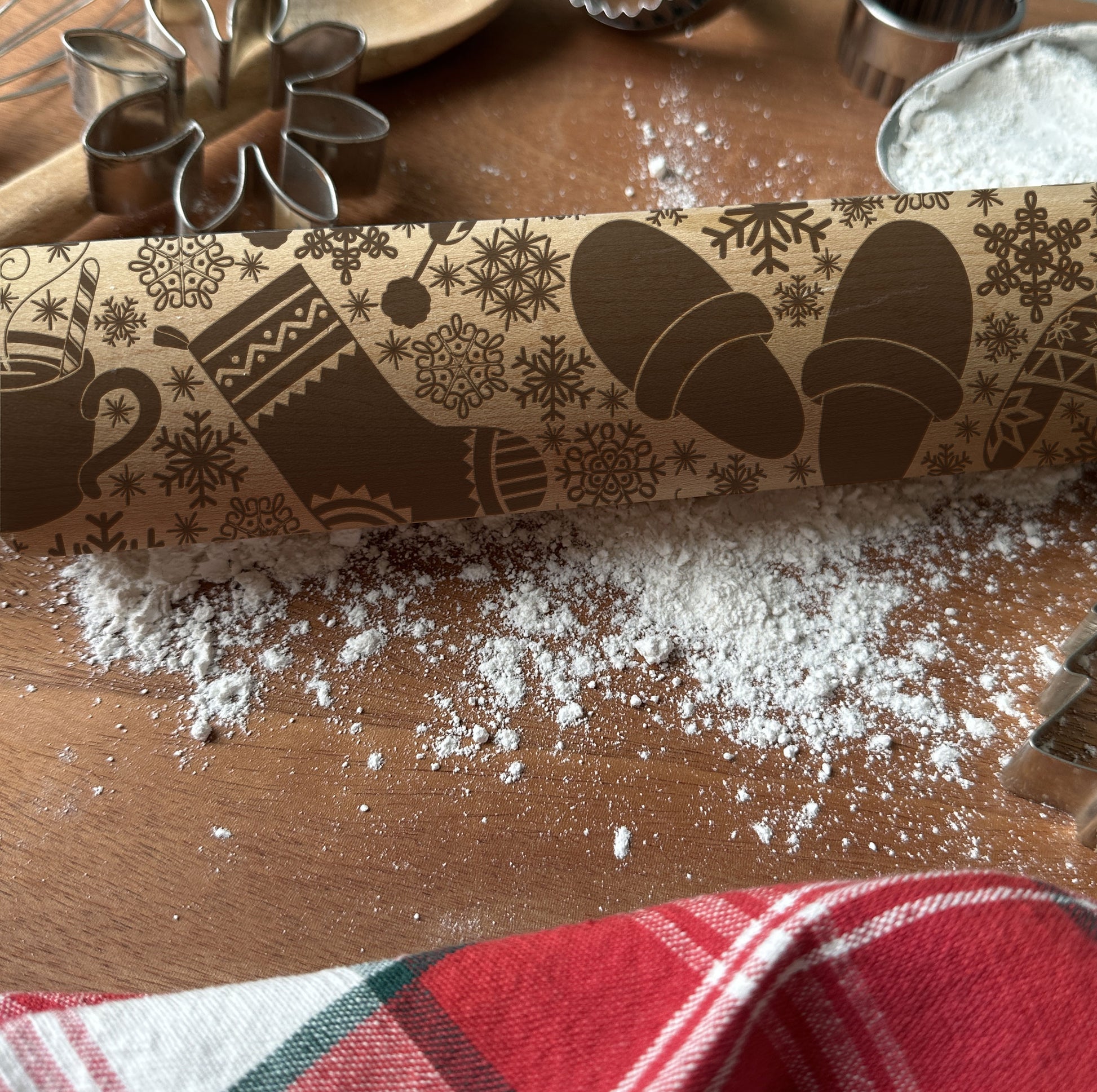 Decorative rolling pin with winter-themed design on a wooden surface with flour.