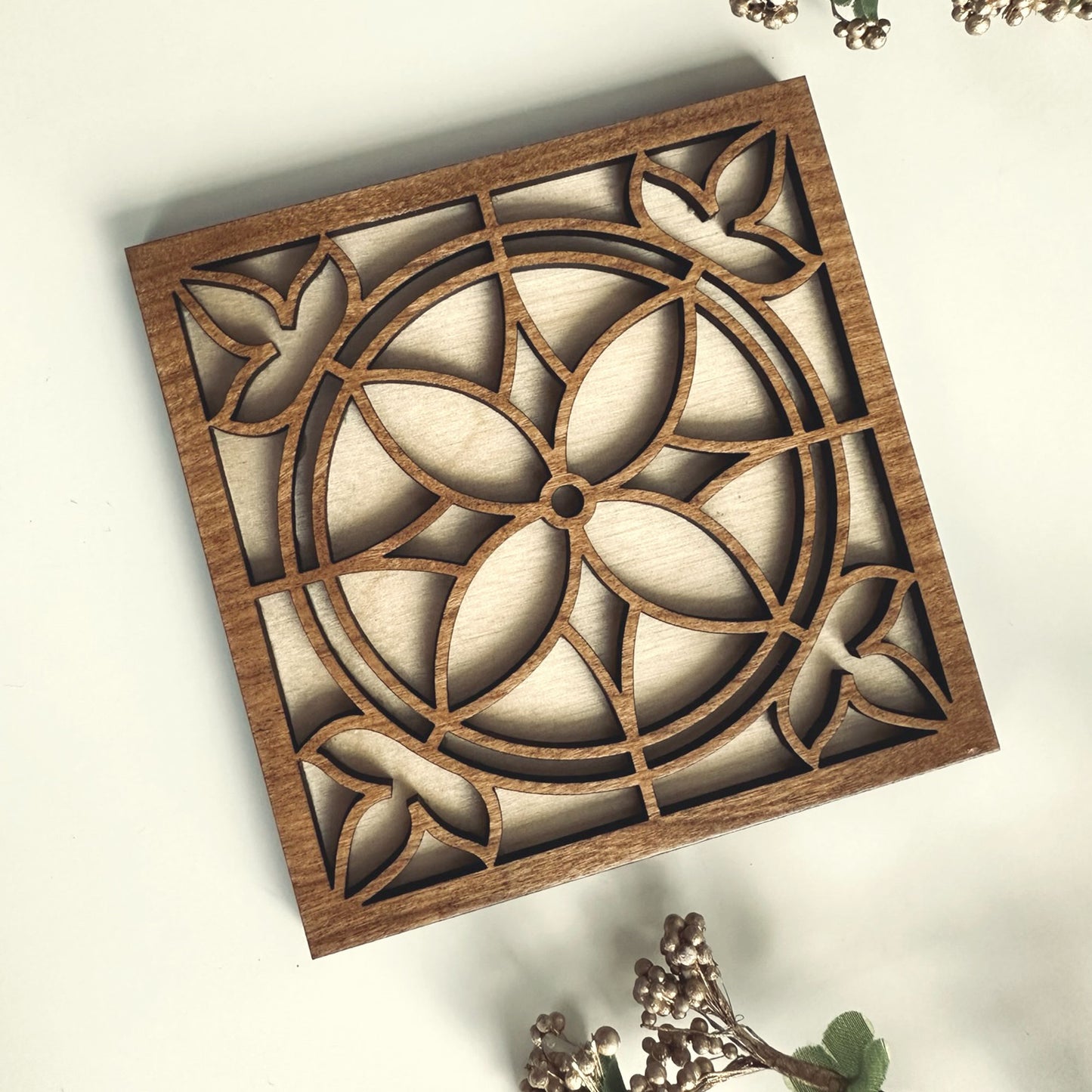Wooden decorative coaster with intricate cut-out design on a light background