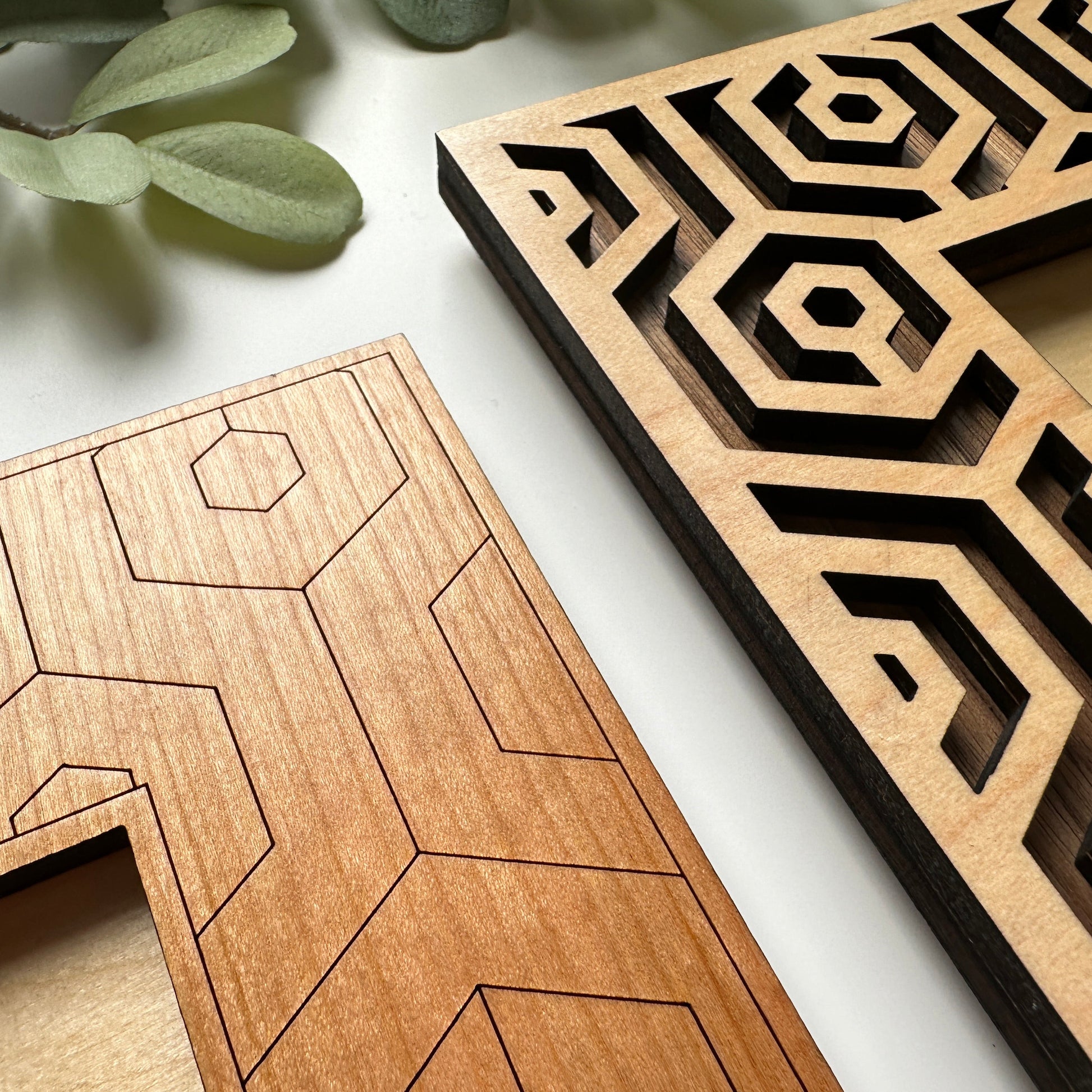 Two wooden letter 'A' shapes with geometric cutouts on a light background.