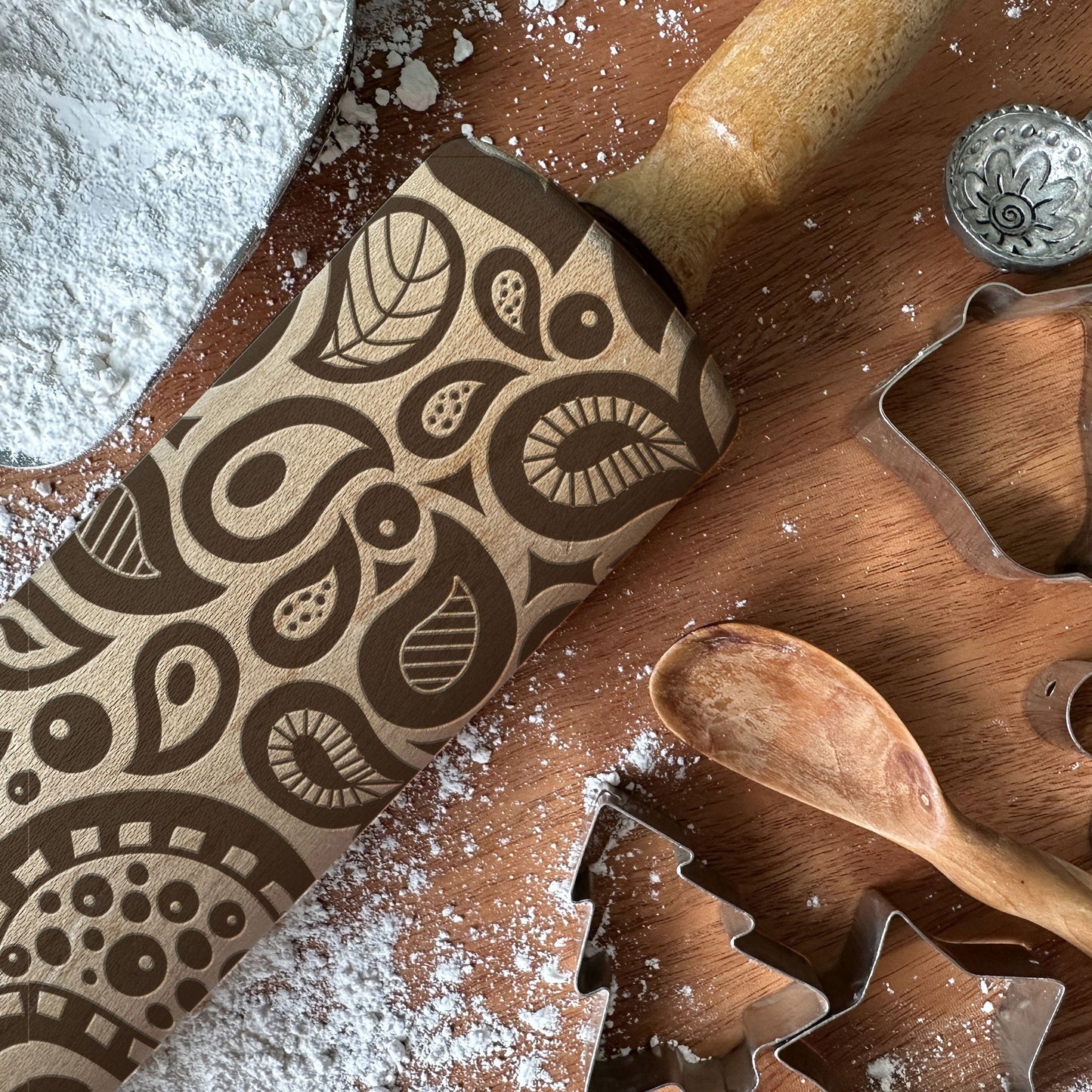 Wooden cookie cutters with decorative patterns on a wooden board with flour.