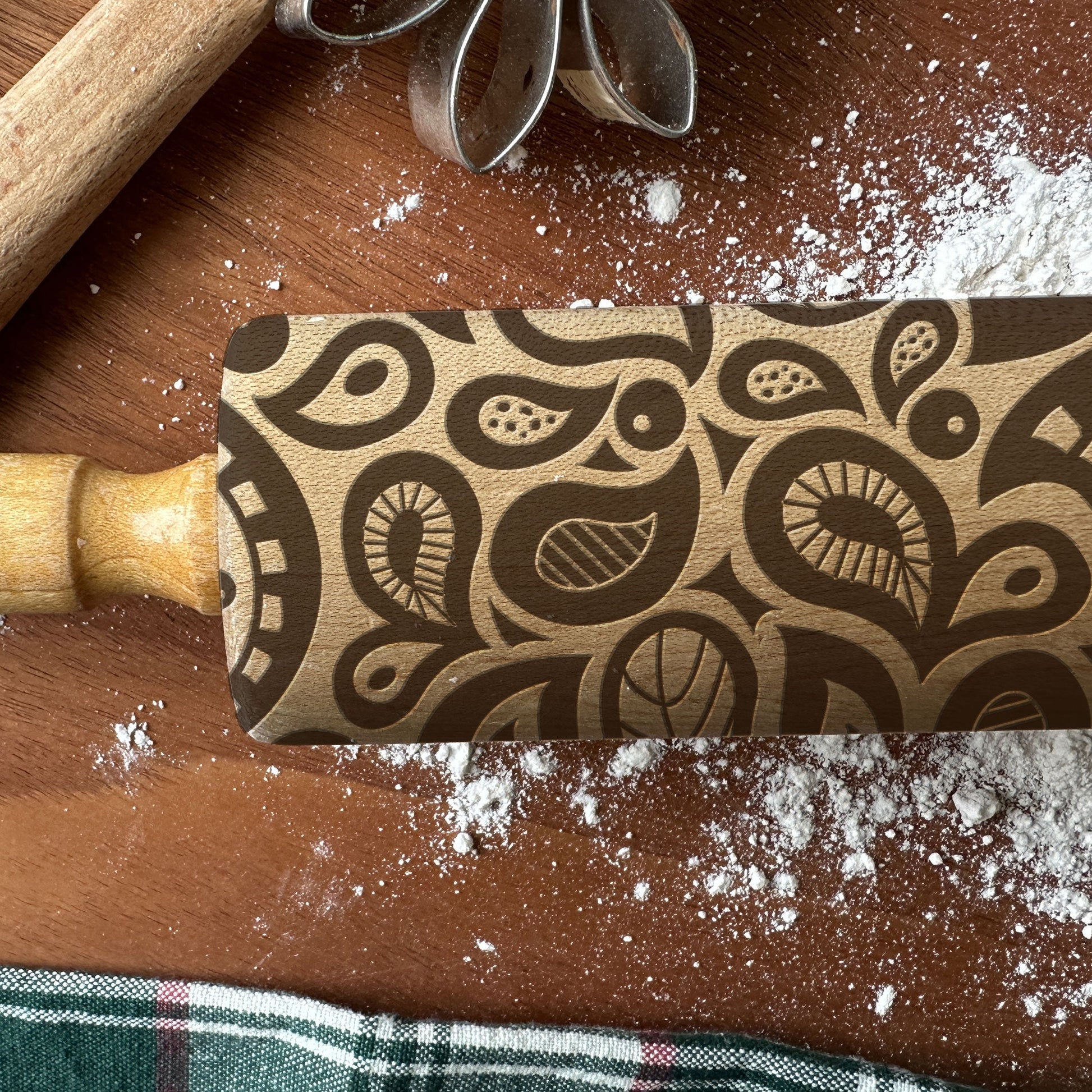 Wooden rolling pin with decorative pattern on a wooden surface with flour.