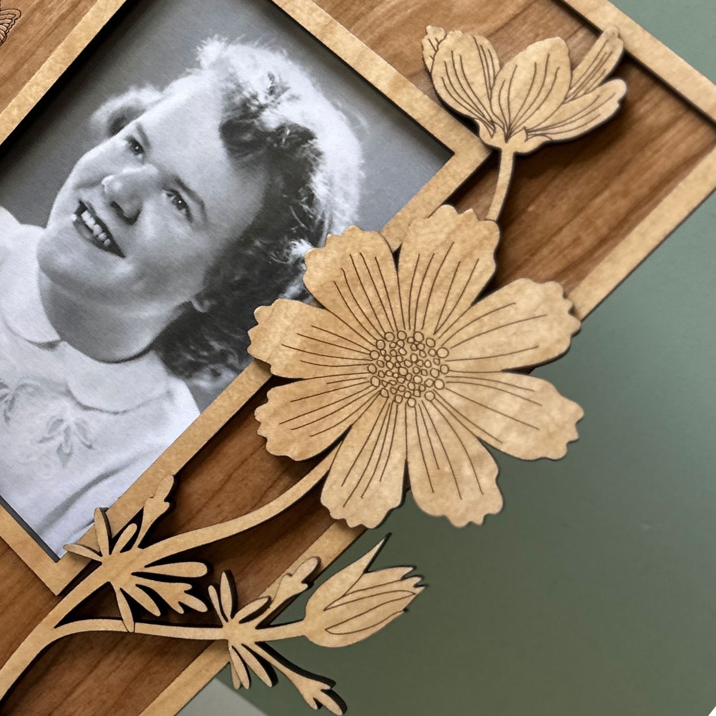 Wooden photo frame with floral designs and a black and white photo of a woman.