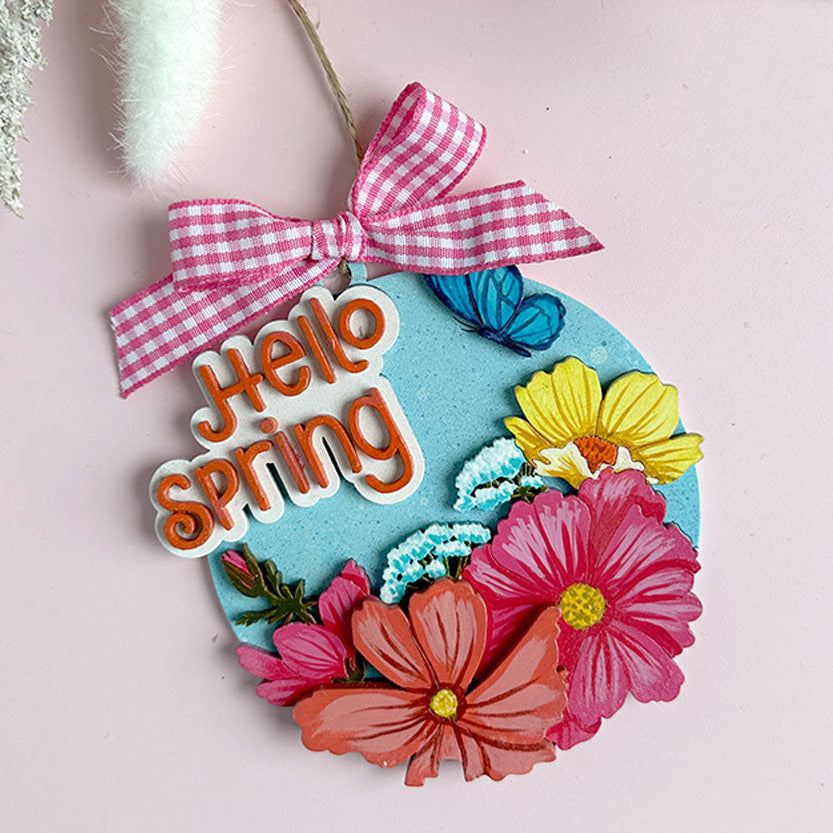 Decorative sign with 'Hello Spring' text and colorful flowers on a pink background