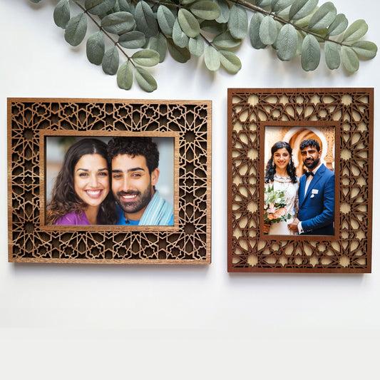Two wooden photo frames with cut-out designs, each containing a couple's portrait.