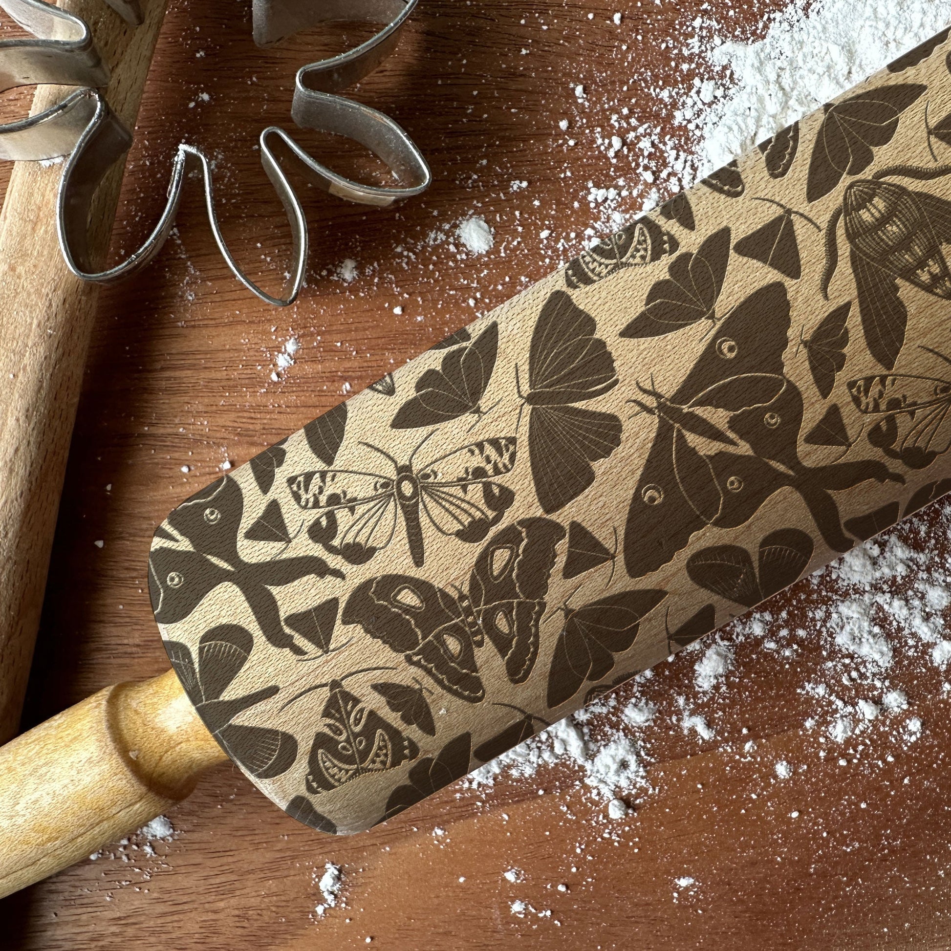 Rolling pin with butterfly pattern on a wooden surface with flour