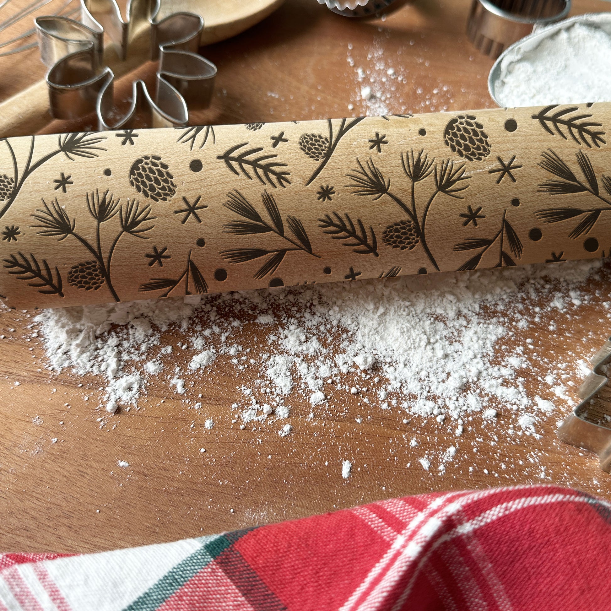 Wooden rolling pin with engraved floral patterns on a wooden surface with flour.
